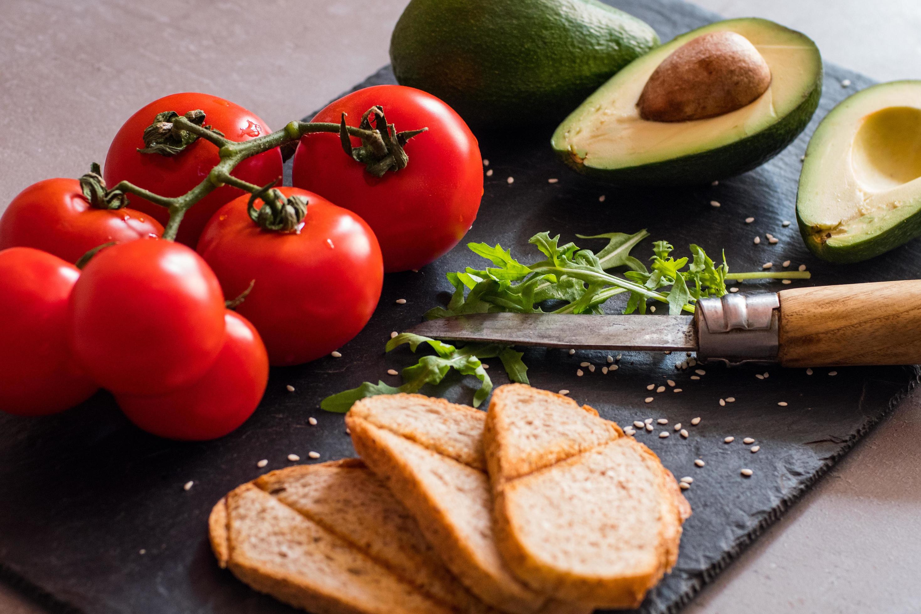 Tomatos and avocado on black table close up, colorful healthy food Stock Free