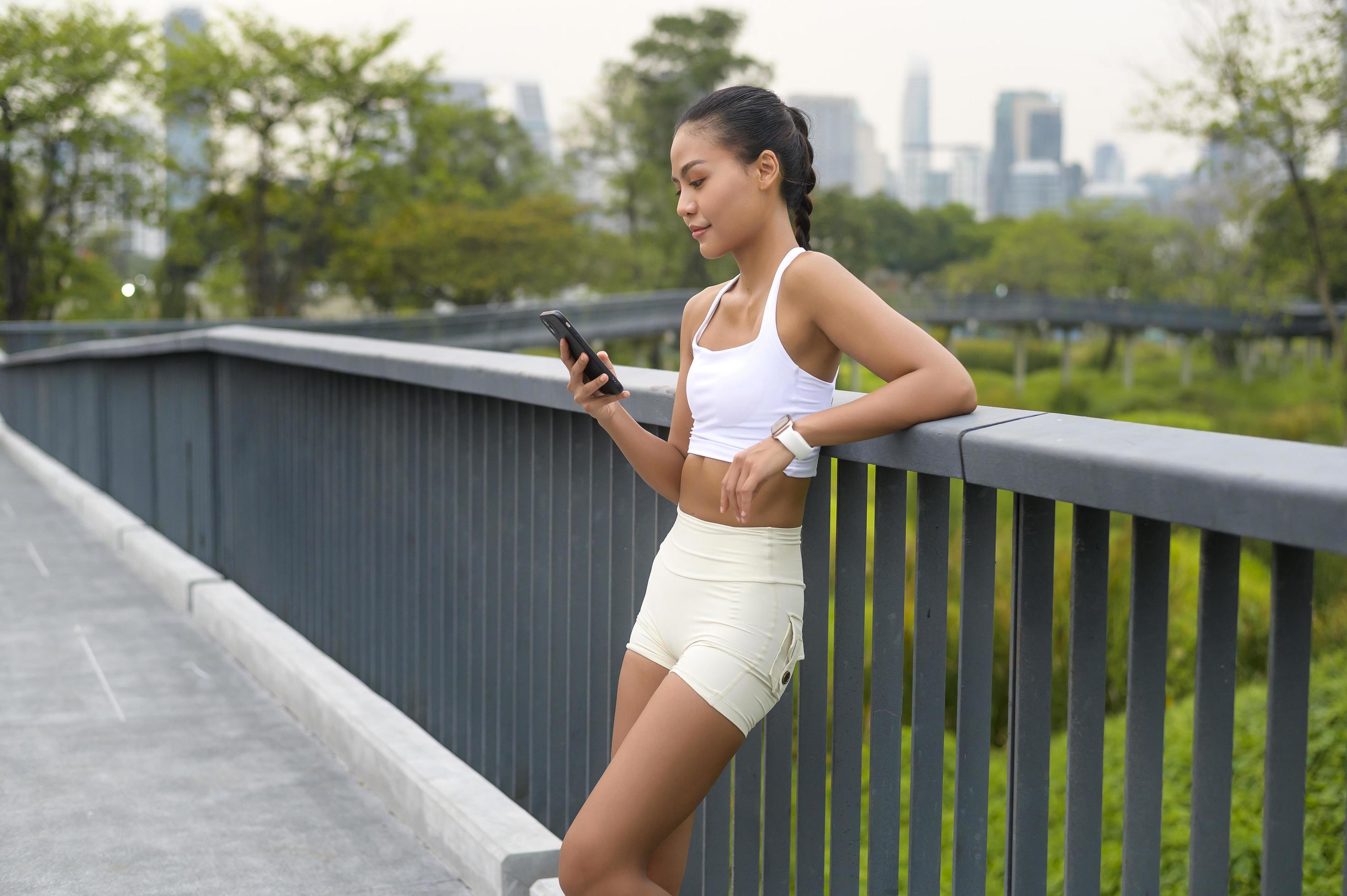 Young fitness woman in sportswear using smart phone while exercising in city park, Healthy and Lifestyles. Stock Free