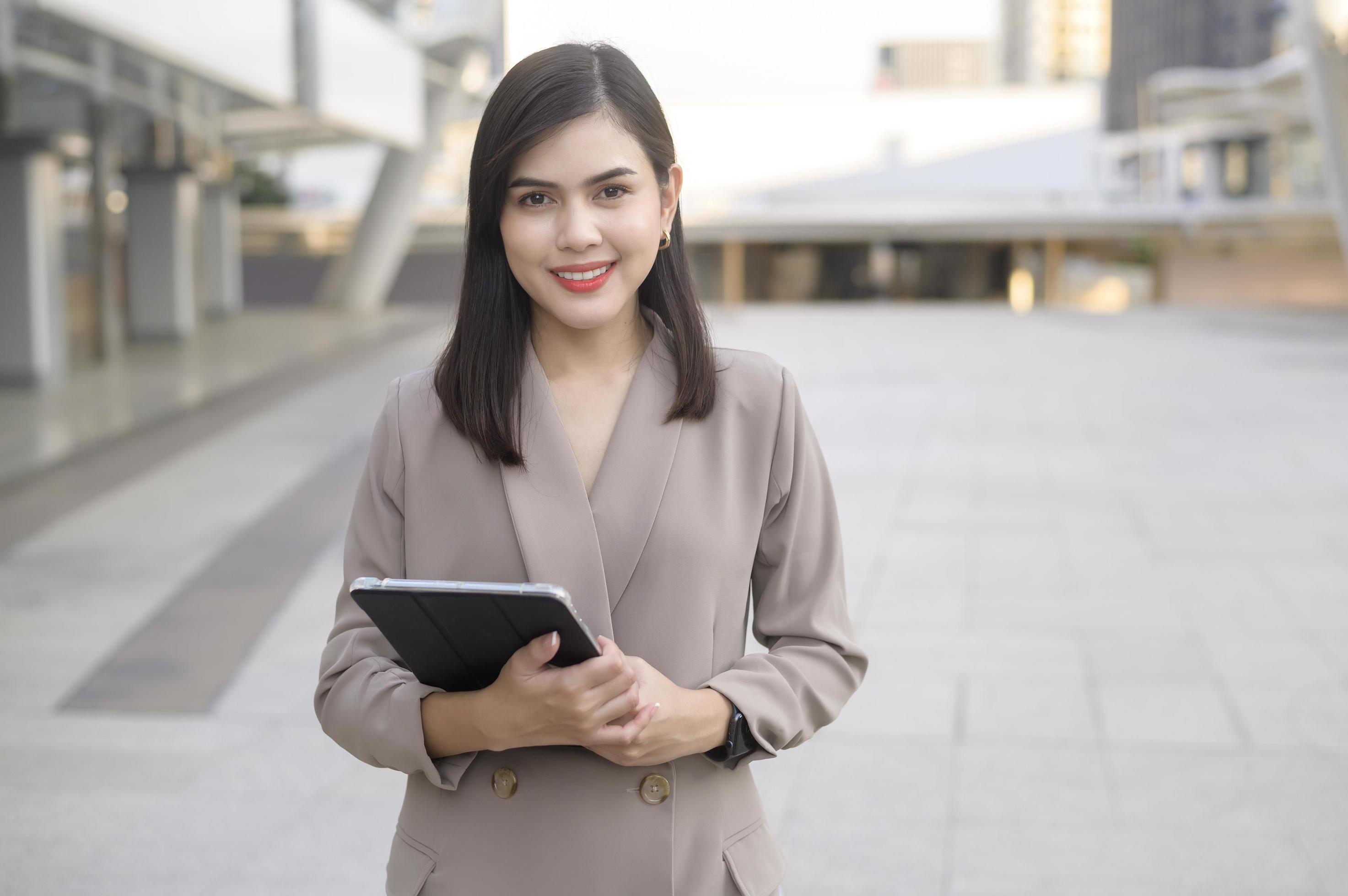 A young beautiful businesswoman is using tablet in Modern city , business technology , city lifestyle concept Stock Free