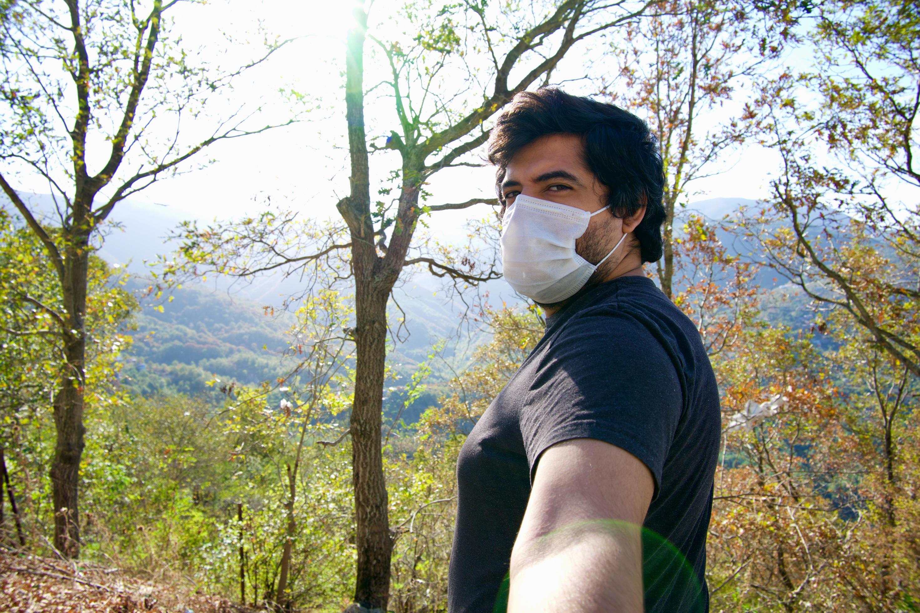 Man wearing a face mask and takes a selfie in nature. Stock Free