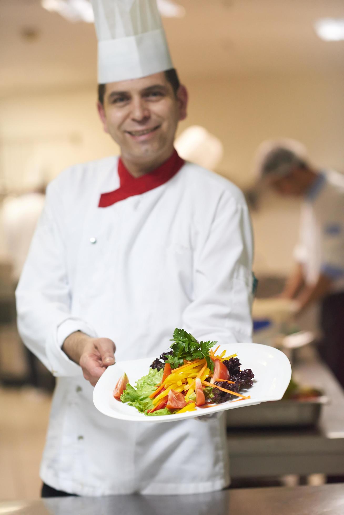 chef in hotel kitchen preparing and decorating food Stock Free