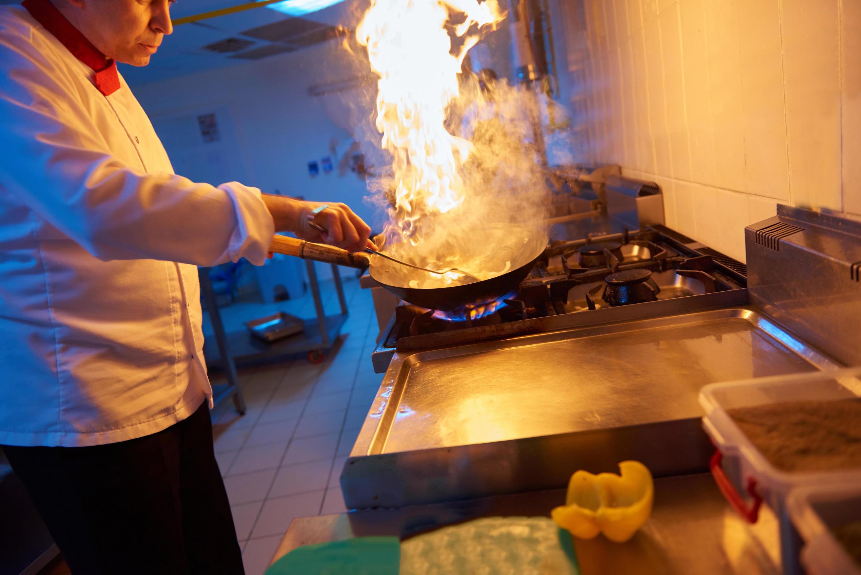 chef in hotel kitchen prepare food with fire Stock Free