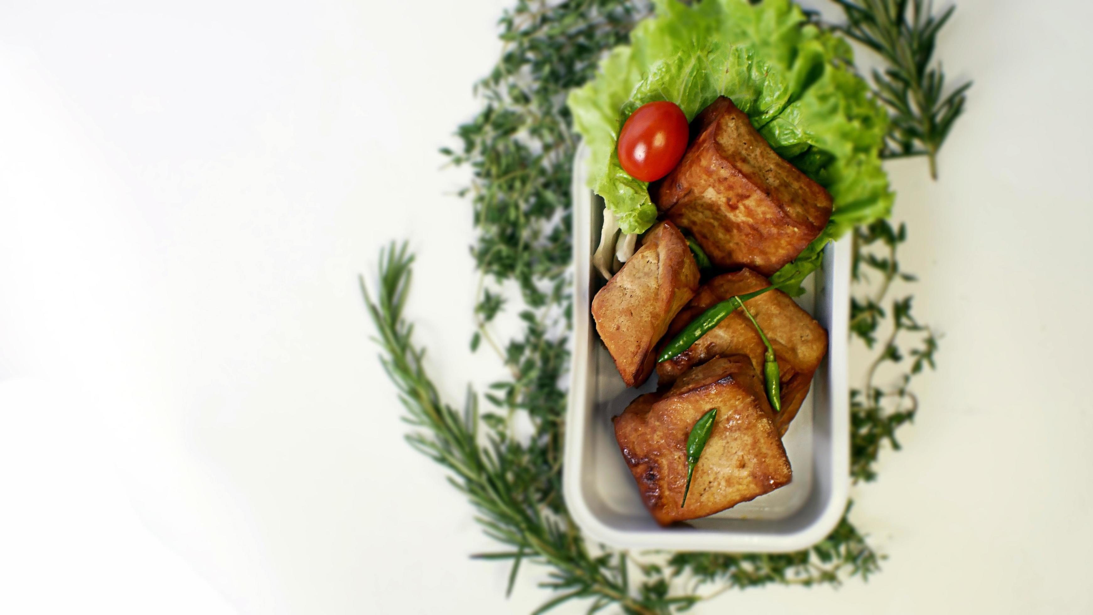 Fried tofu, small tomatoes and green chilies along with lettuce in one aluminum container, Indonesian street food on a white background Stock Free