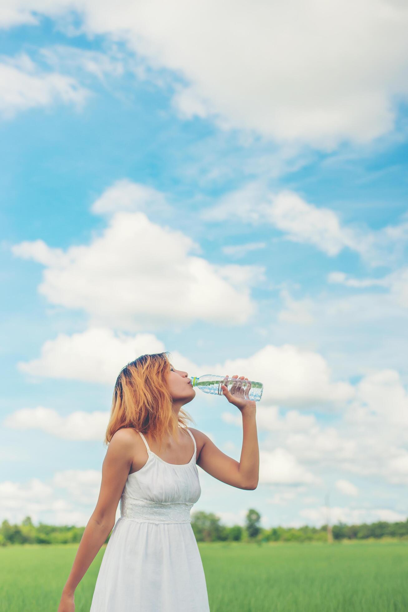 Women lifestyle concept young beautiful woman with white dress drinking water at summer green park. Stock Free