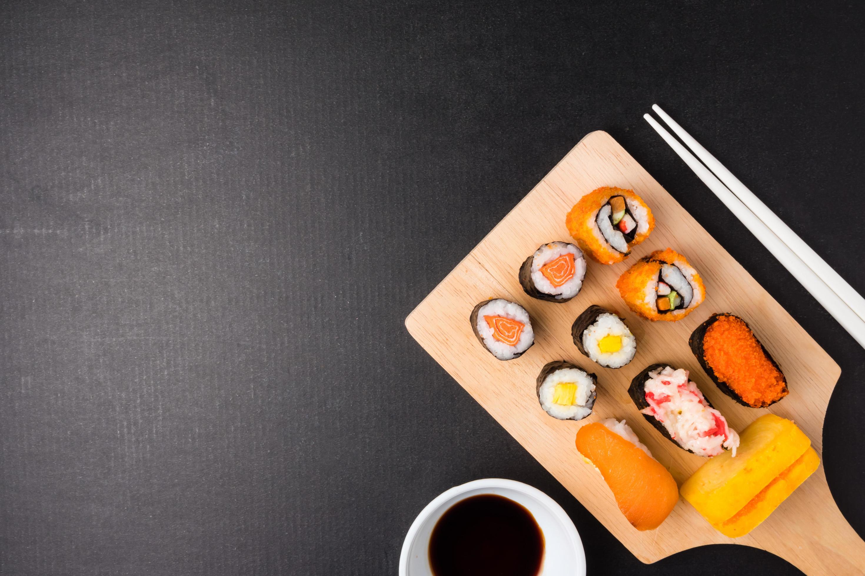 Top view of Sushi set on wooden tray with chopsticks and sauce on black background, Japanese food. Free space for text Stock Free