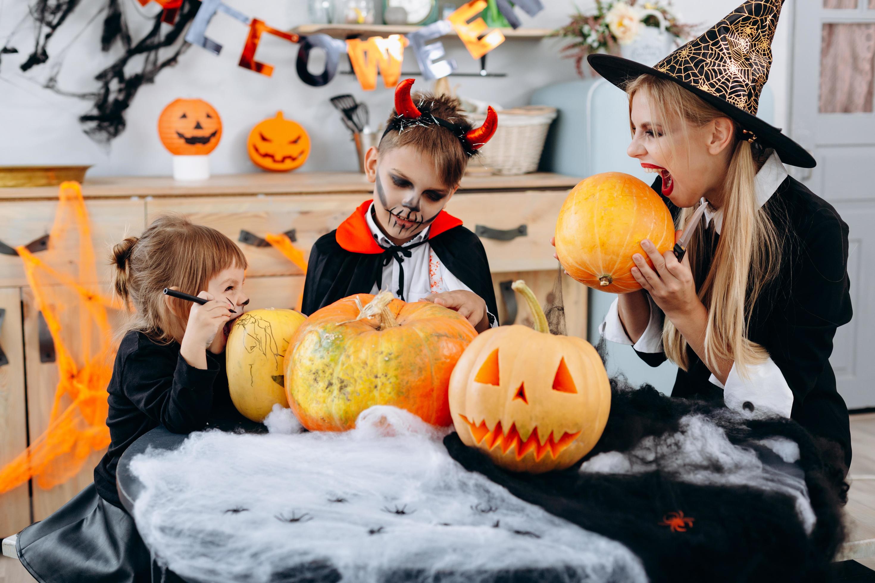 Family have funny time at home. Mother and daughter going to bite a pumpkin -Halloween concept Stock Free