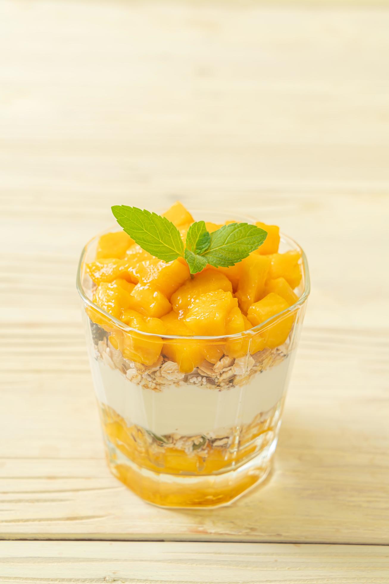 Fresh mango yogurt with granola in glass – healthy food style Stock Free