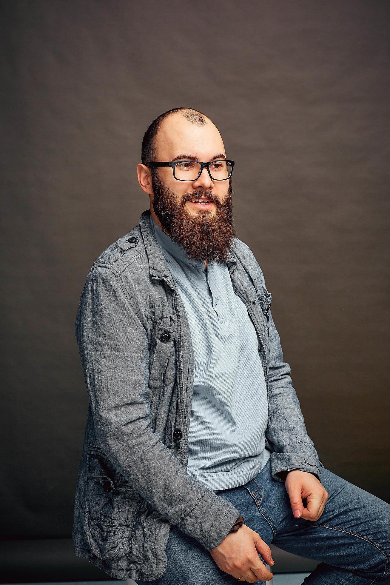 lifestyle successful young man with glasses , beard, fashionable denim jacket looking forward,male portrait in the Studio on a uniform background. Stock Free