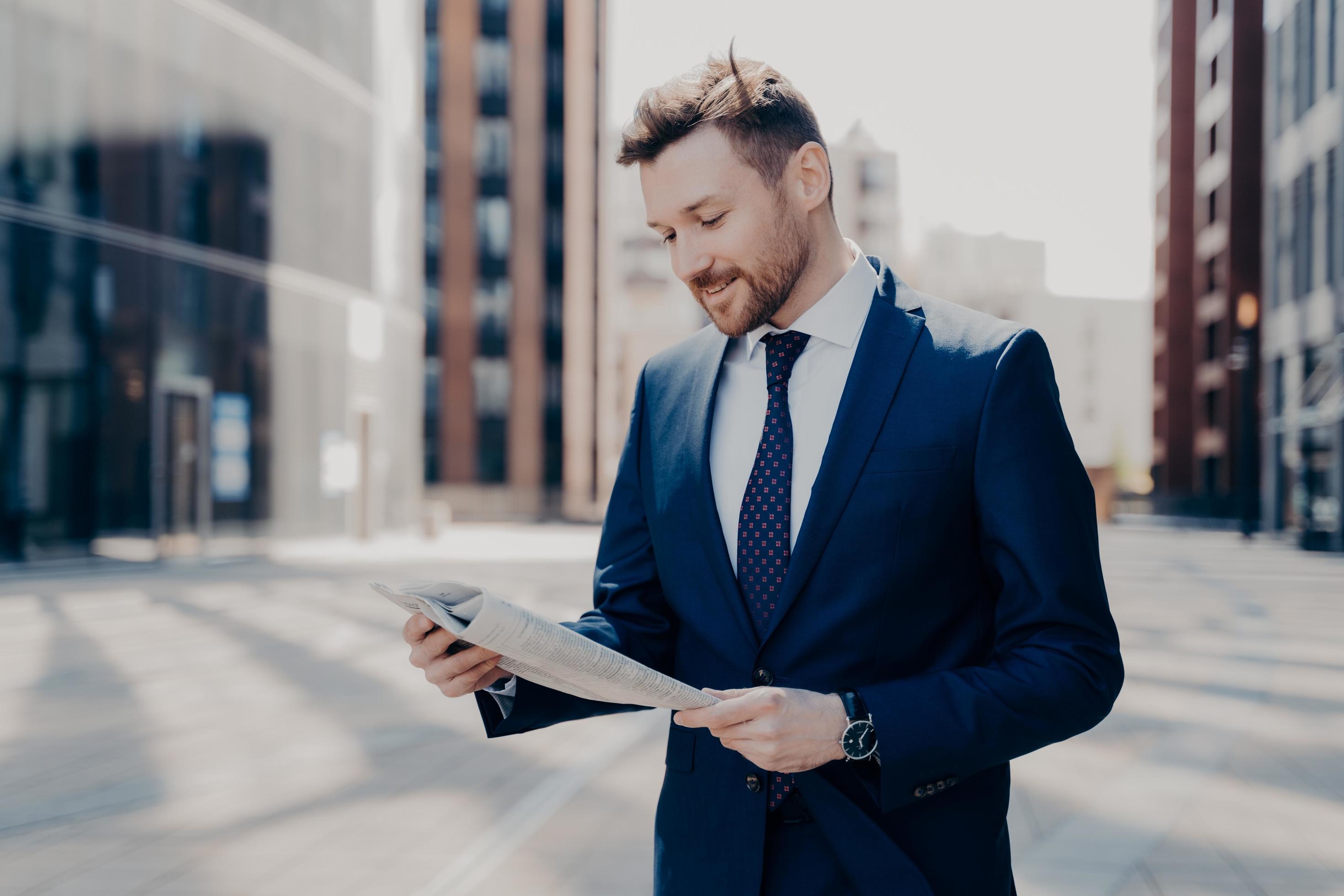 Business owner reading positive news in newspaper while walking to work Stock Free