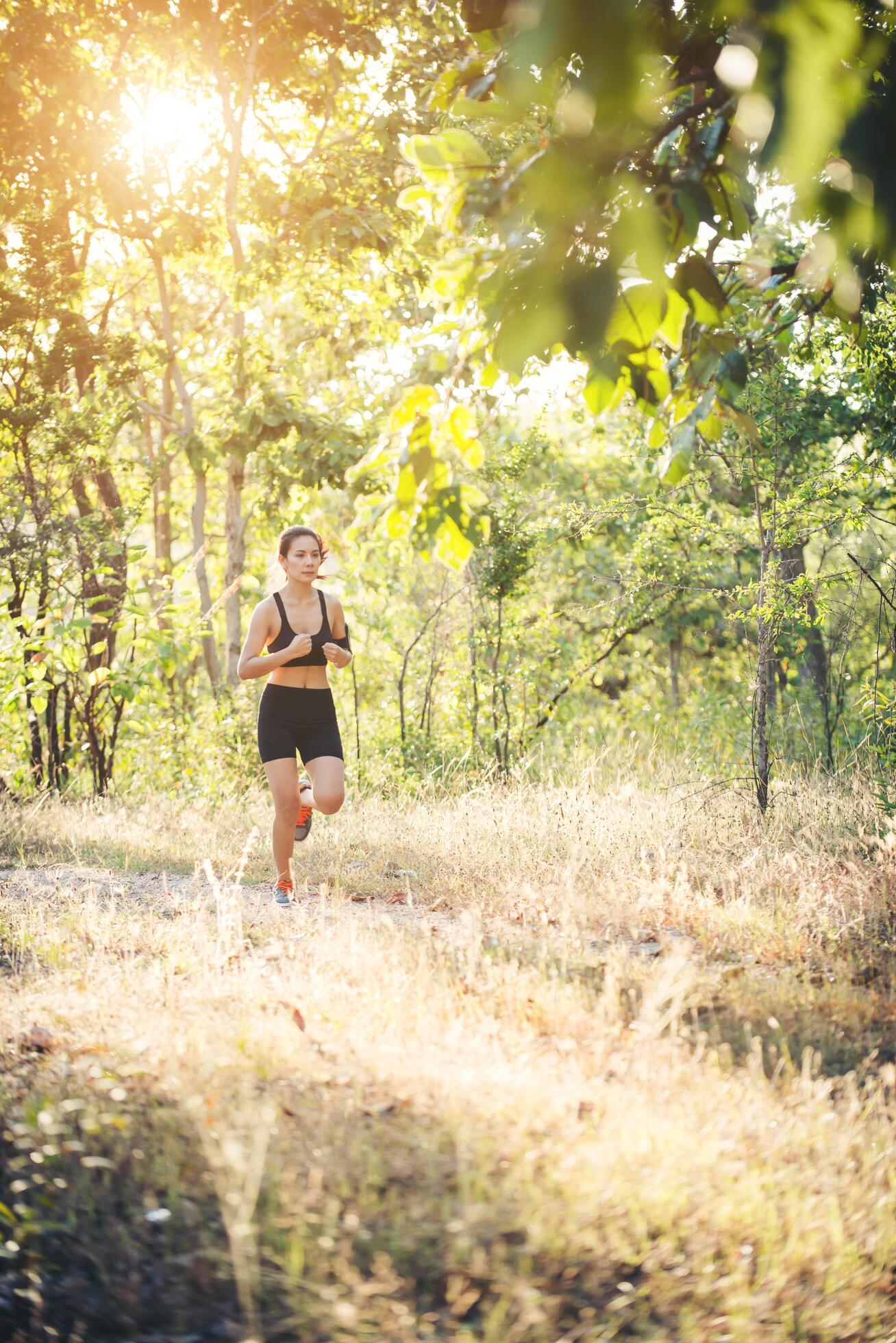 Young woman jogging on rural road in forest nature. Stock Free