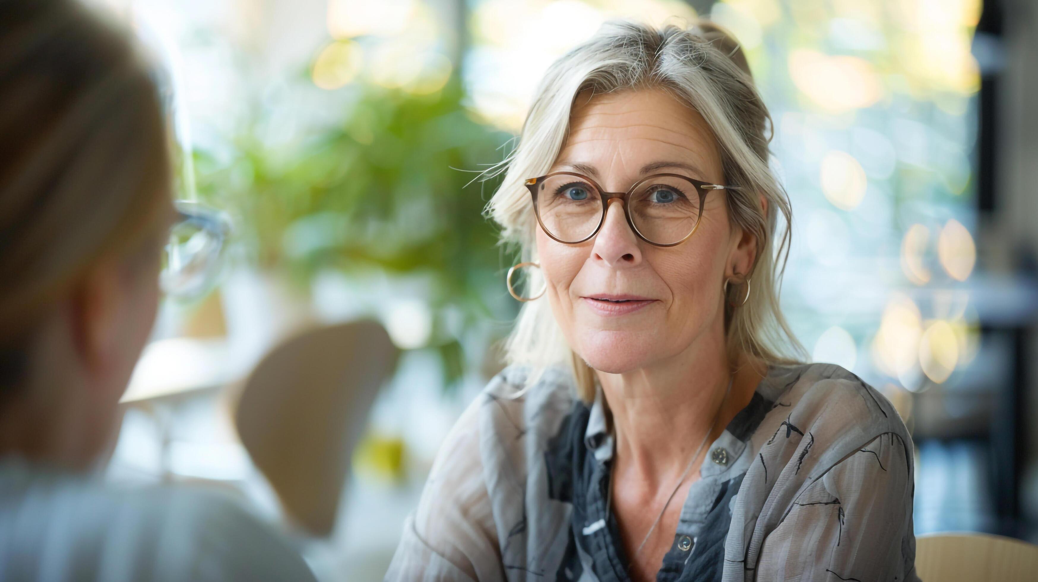 Woman in glasses conversing with lady in cafe Stock Free