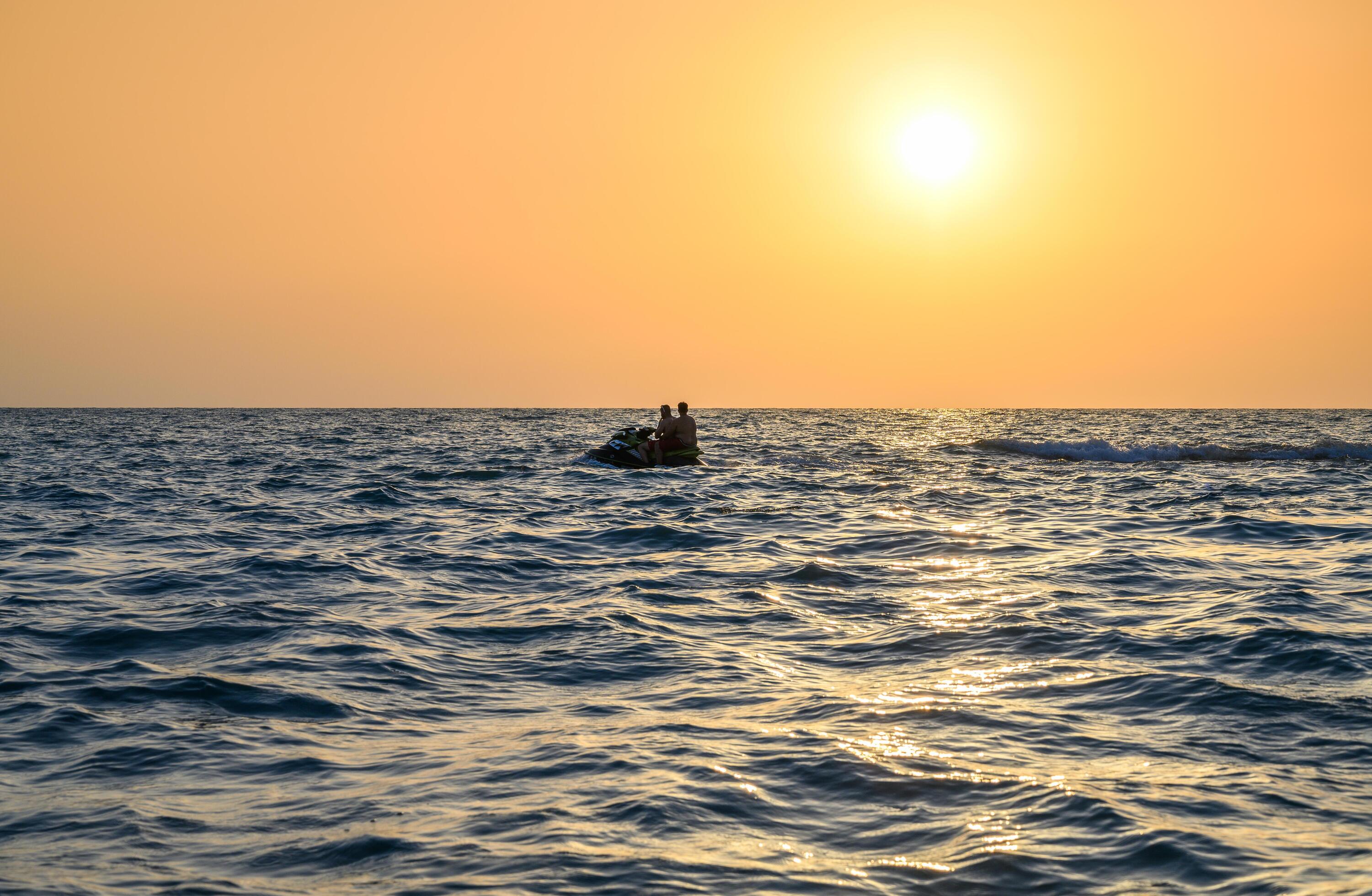 A man driving a jet ski , stunting and making spray of water drops with a sunlight on background Stock Free