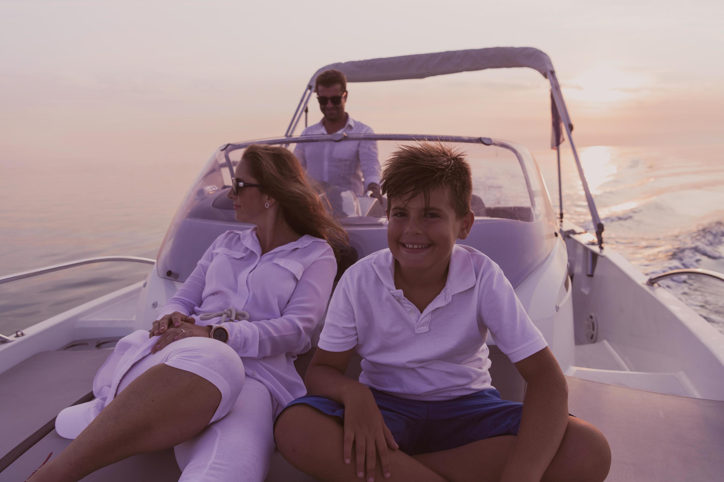 A senior couple in casual outfits with their son enjoy while riding a boat at sea at sunset. The concept of a happy family. Selective focus Stock Free