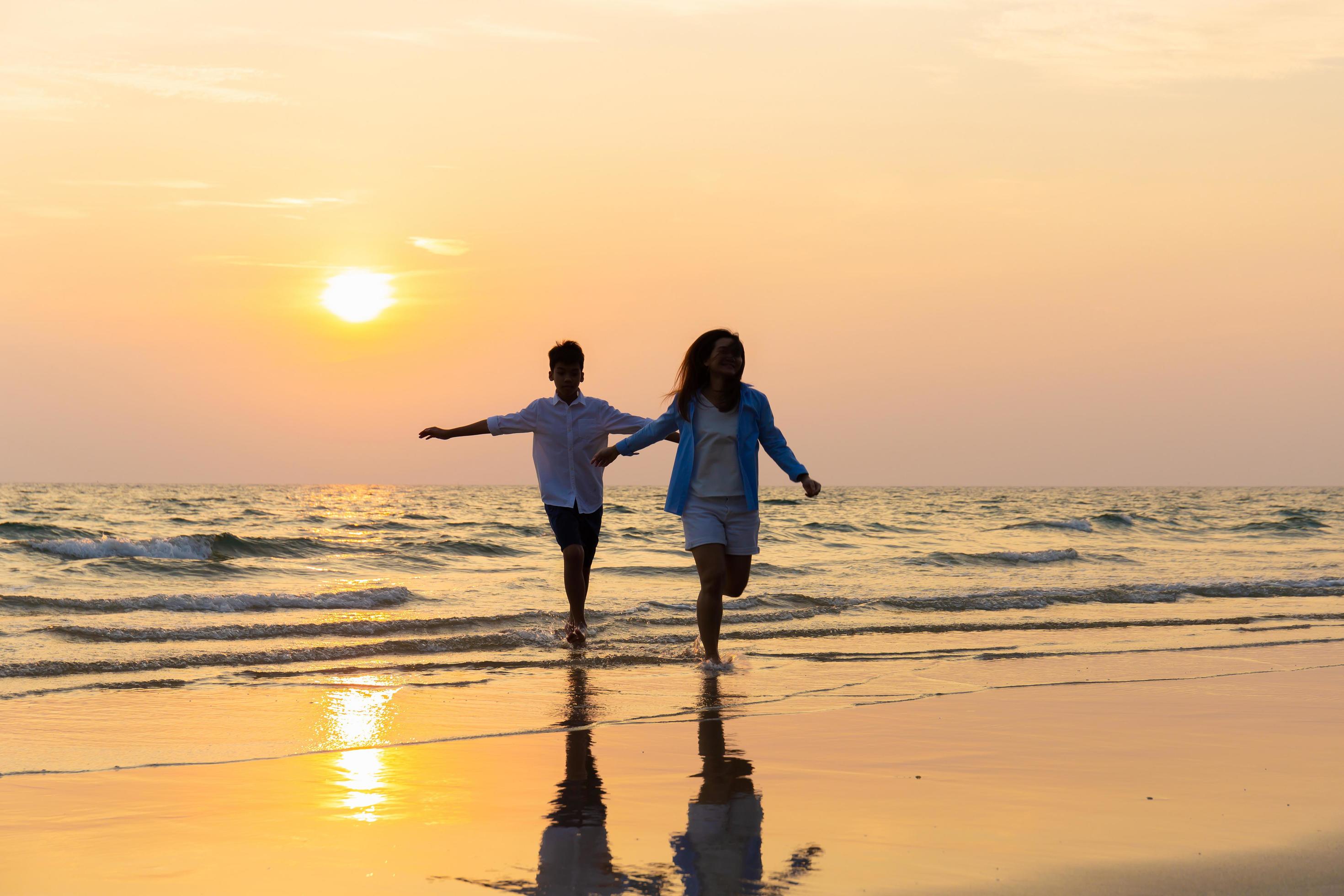 Mother and son running along a beach, Asian happy family parent with child boy running and having fun on the beach Stock Free