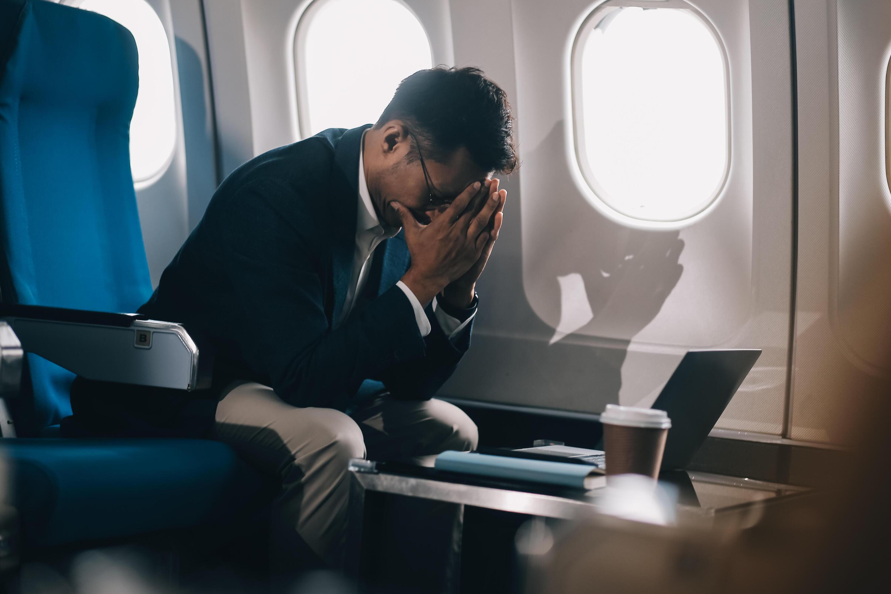 scared man with closed eyes and fingers crossed in private jet Stock Free