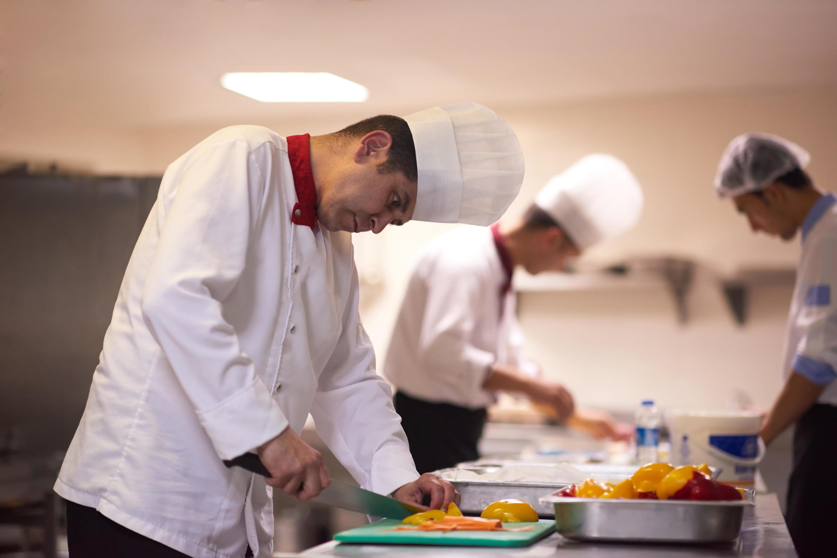 chef in hotel kitchen preparing and decorating food Stock Free