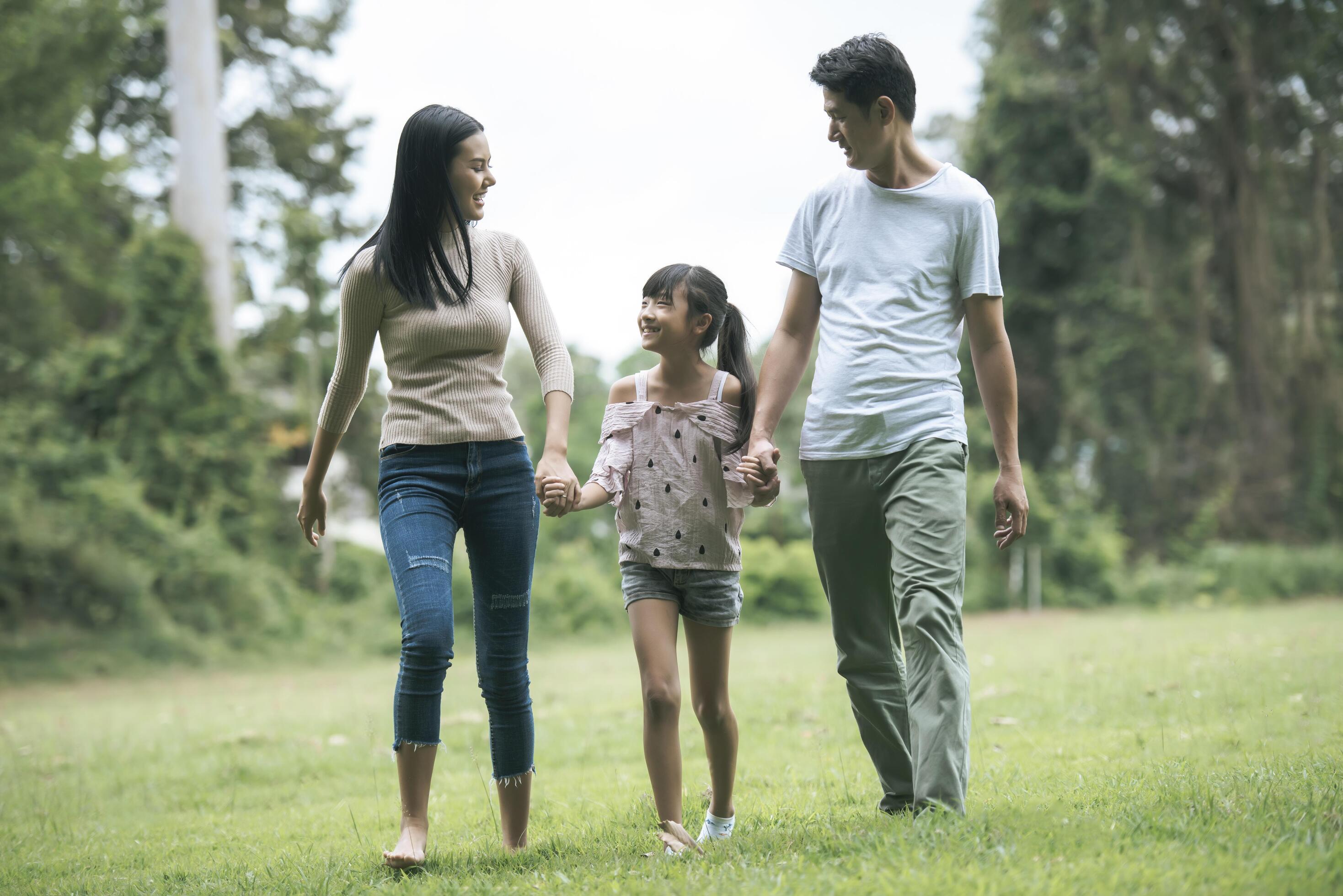 Happy parents and their daughter walking in the park, Happy family concept. Stock Free