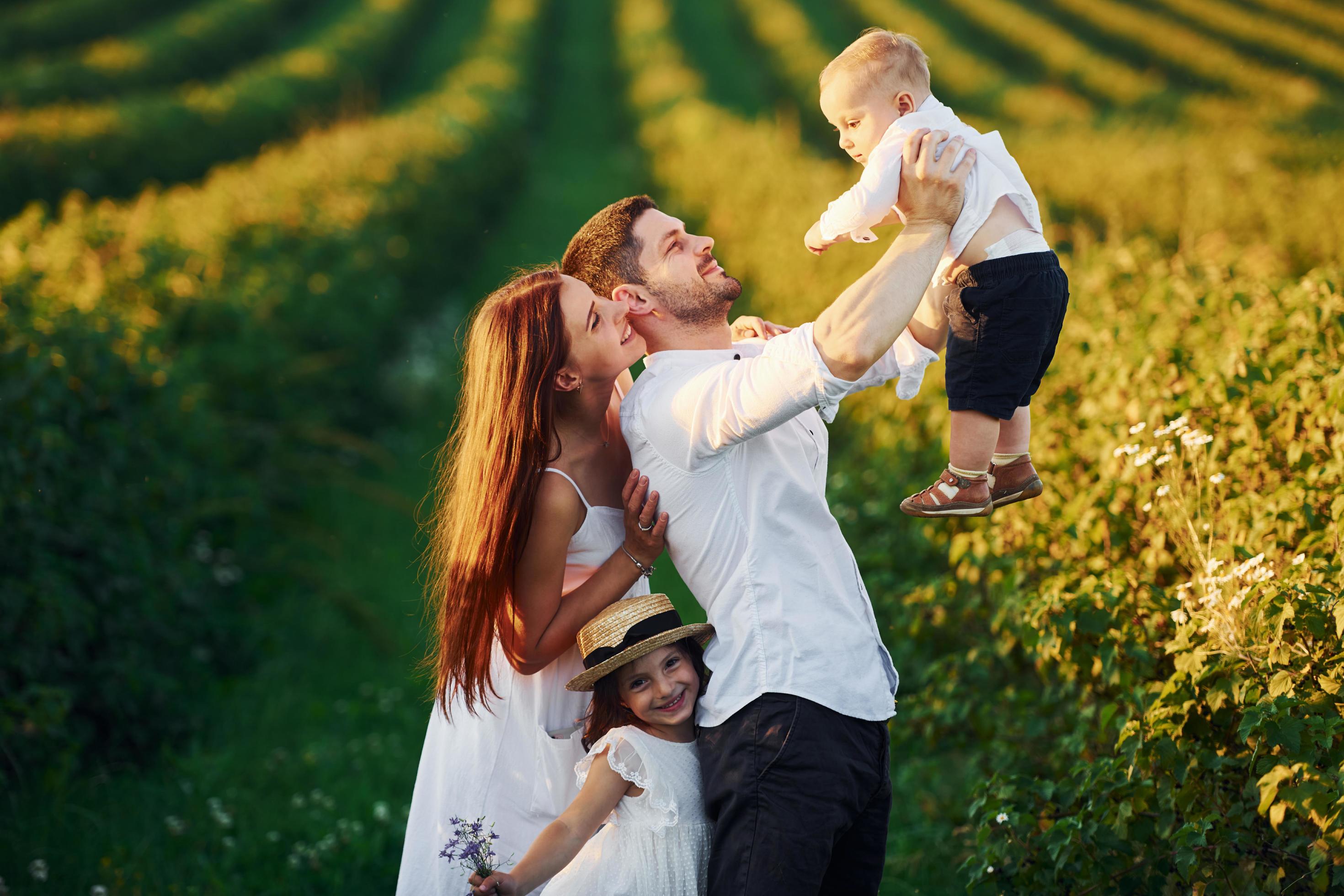 Father, mother with daughter and son spending free time outdoors at sunny day time of summer Stock Free