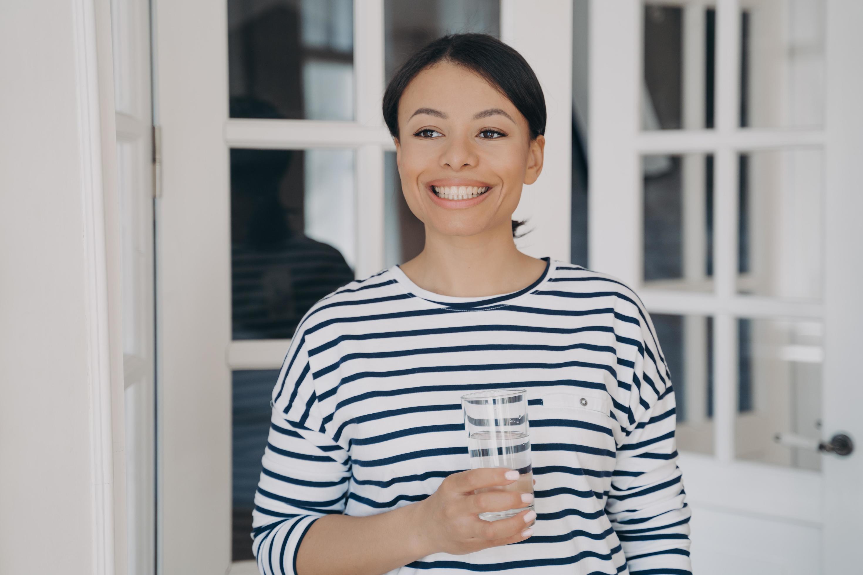 Happy female holding glass of clean water. Healthy lifestyle, wellness. Water filter advertising Stock Free