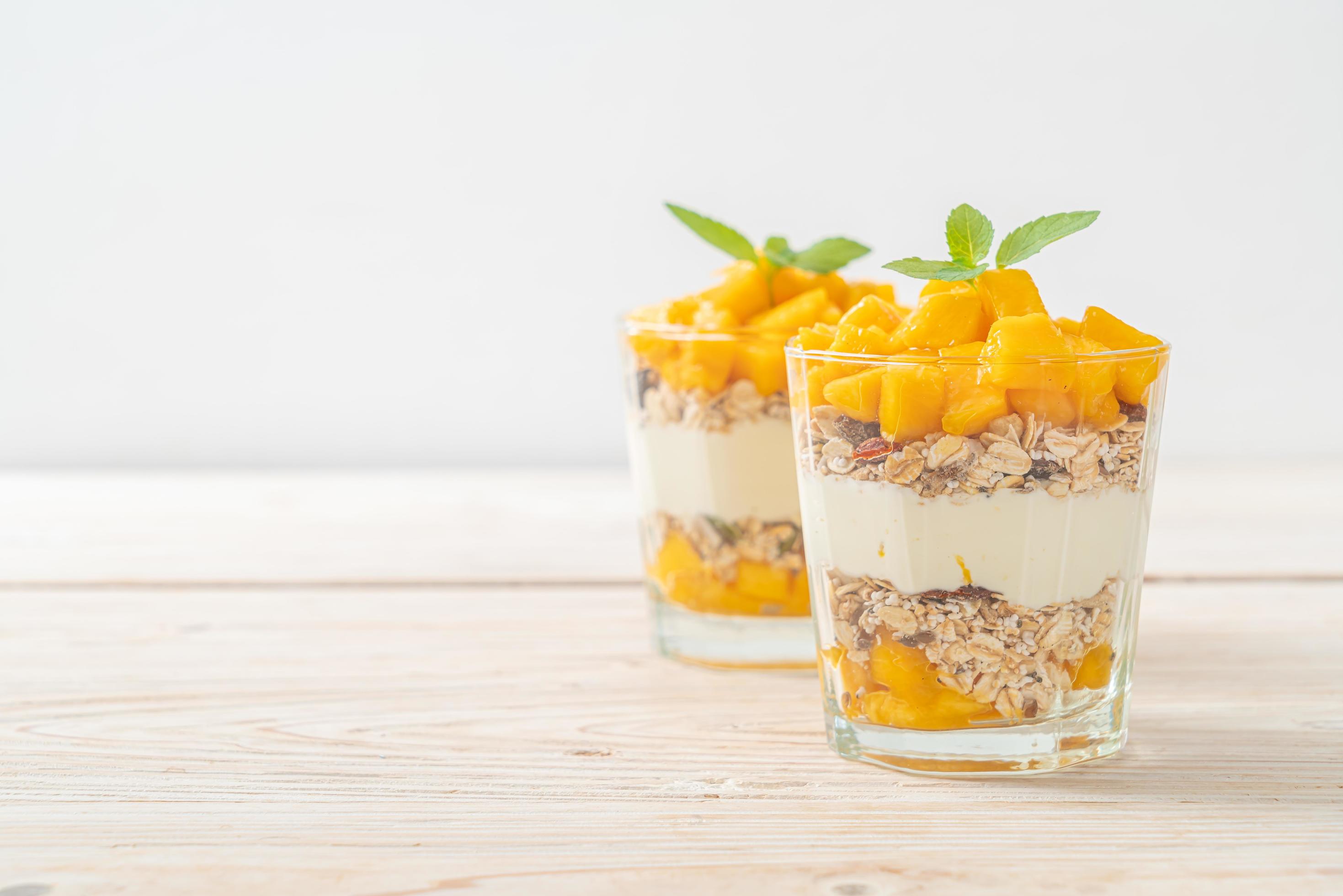 Fresh mango yogurt with granola in glass – healthy food style Stock Free