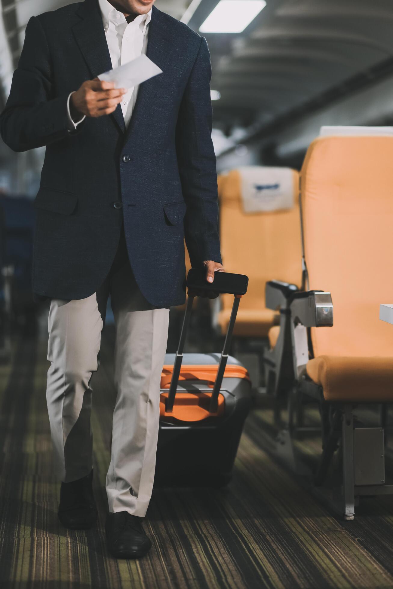 Handsome Asian male passenger takes his carry-on luggage out of the overhead locker after landing at his destination. transportation concept Stock Free