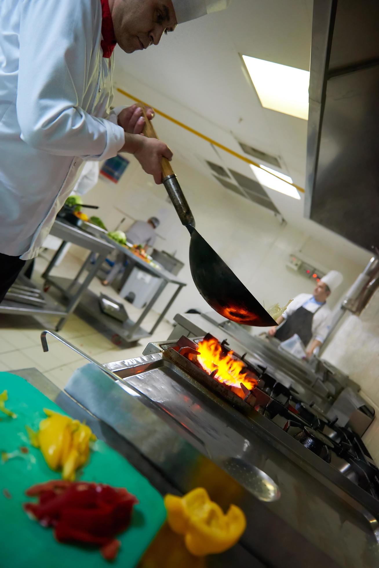 chef in hotel kitchen prepare food with fire Stock Free