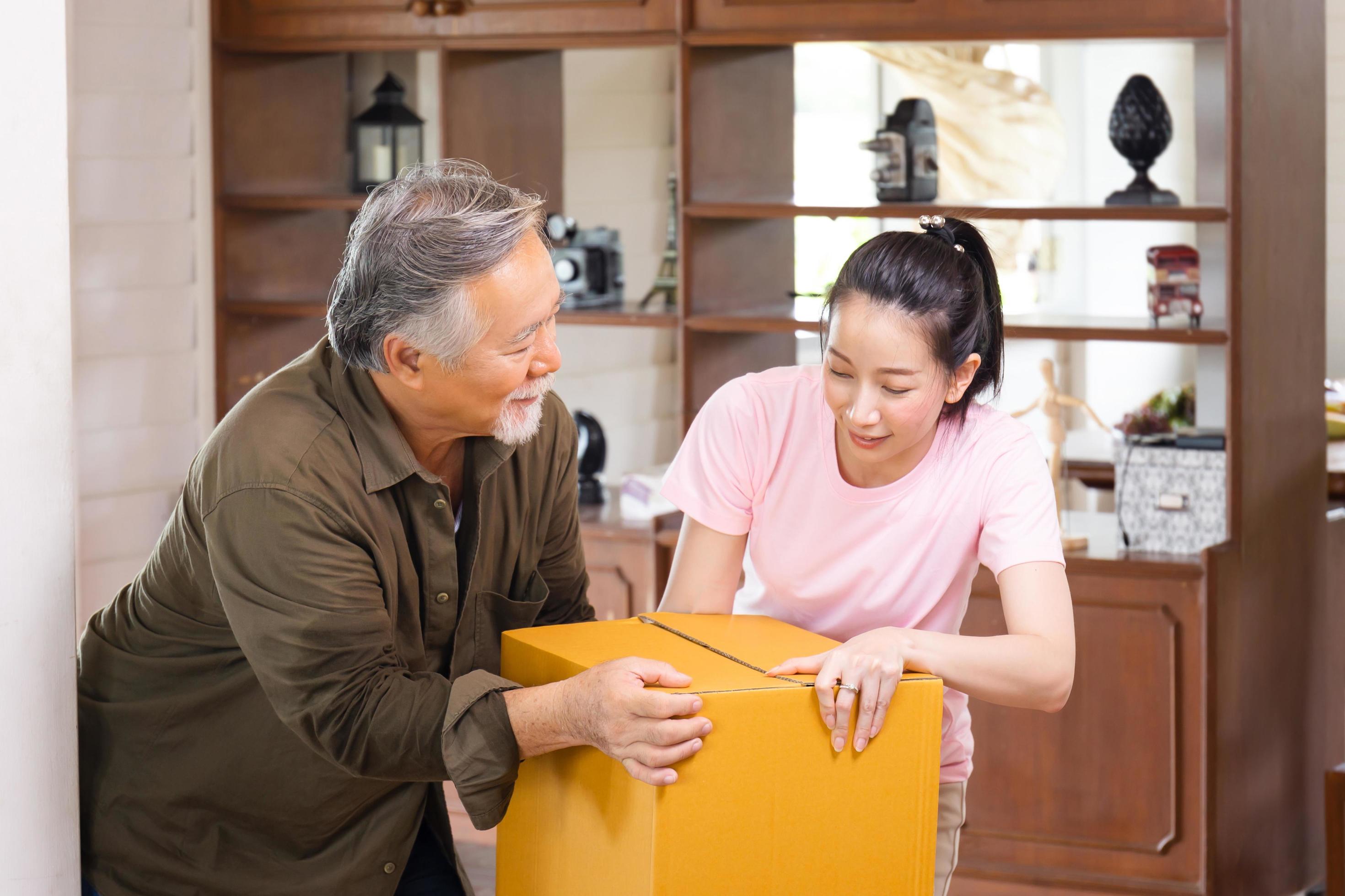 Moving day concepts, Asian family carrying boxes into new home, Happiness middle aged daughter and senior father in new house Stock Free