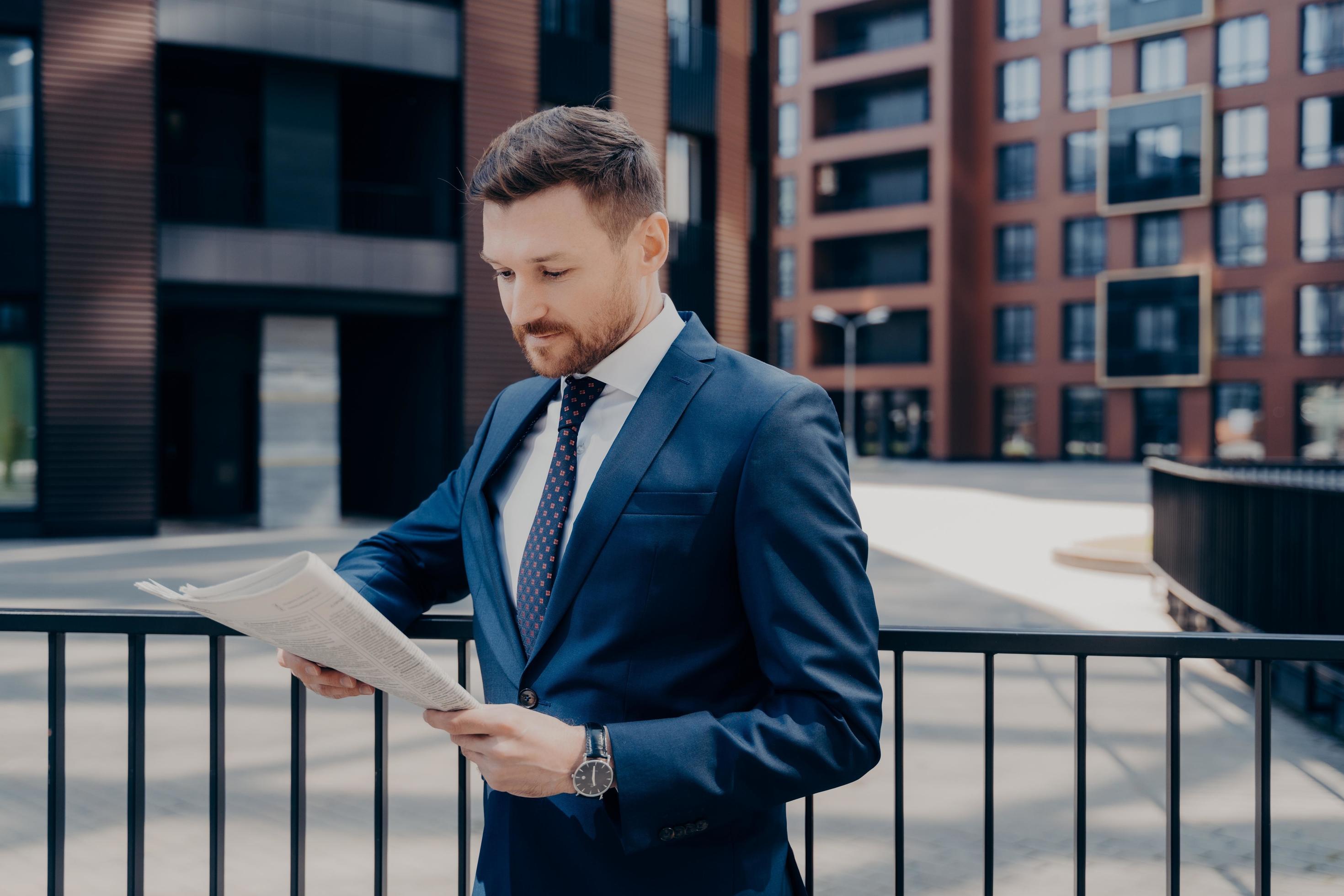 Confident proud CEO dressed in elegant wear reading business publication on early morning Stock Free