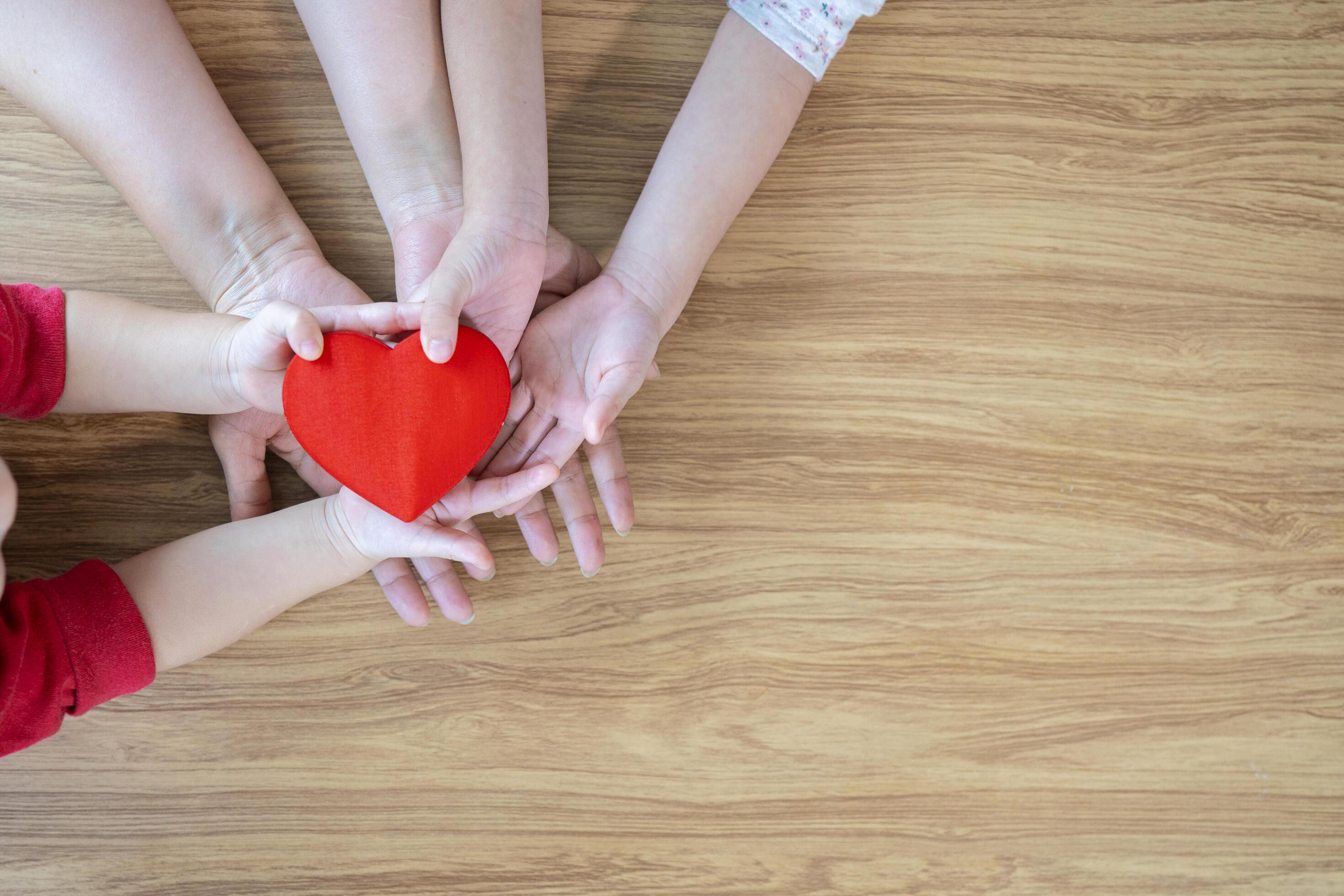 adult and child hands holding red heart on aqua background, heart health, donation, CSR concept, world heart day, world health day, family day Stock Free