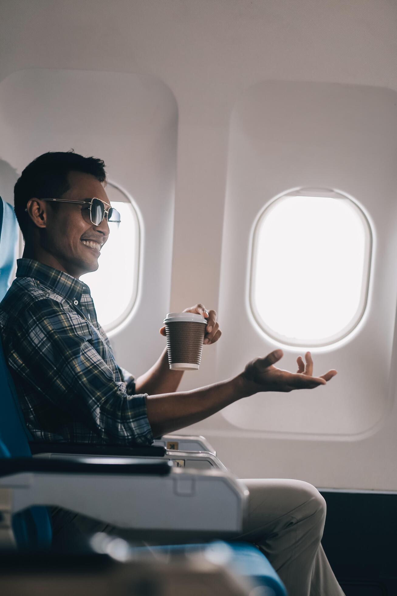 Asian man enjoying enjoys a coffee comfortable flight while sitting in the airplane cabin, Passengers near the window. Stock Free