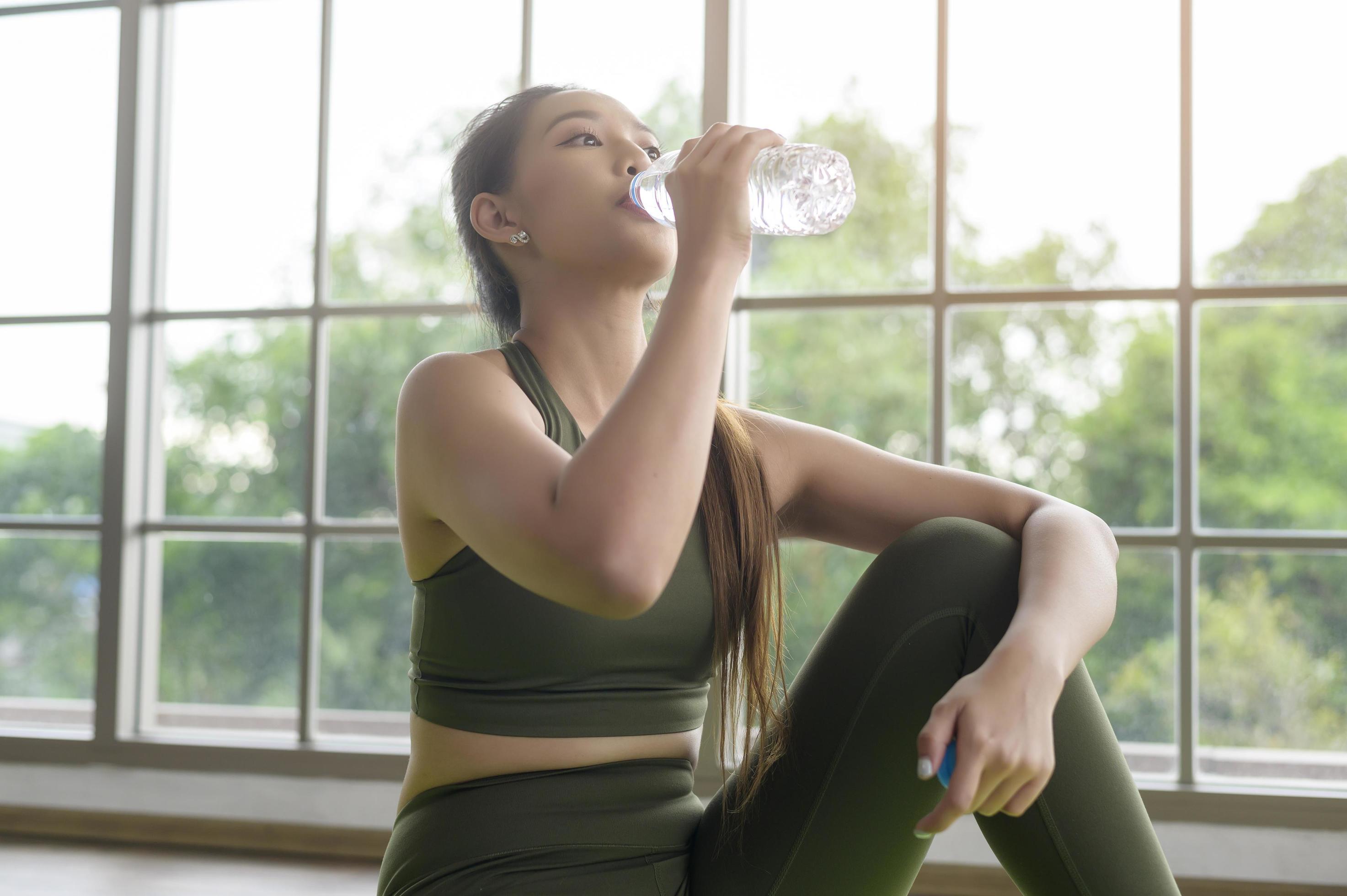 Young fitness woman in sportswear drinking water after exercising at home, Healthy and Lifestyles. Stock Free