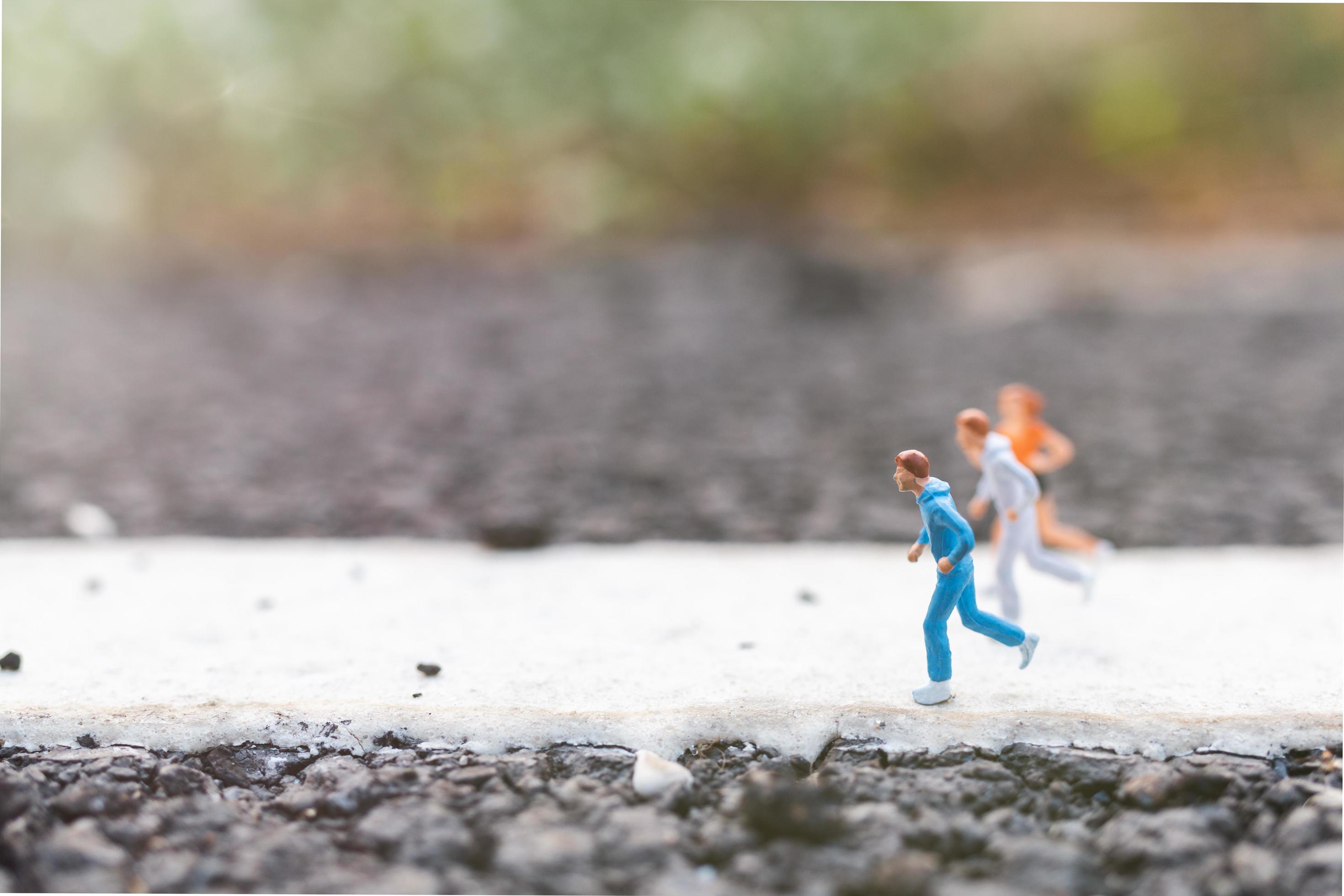 Miniature people running on a street, health and lifestyle concept Stock Free