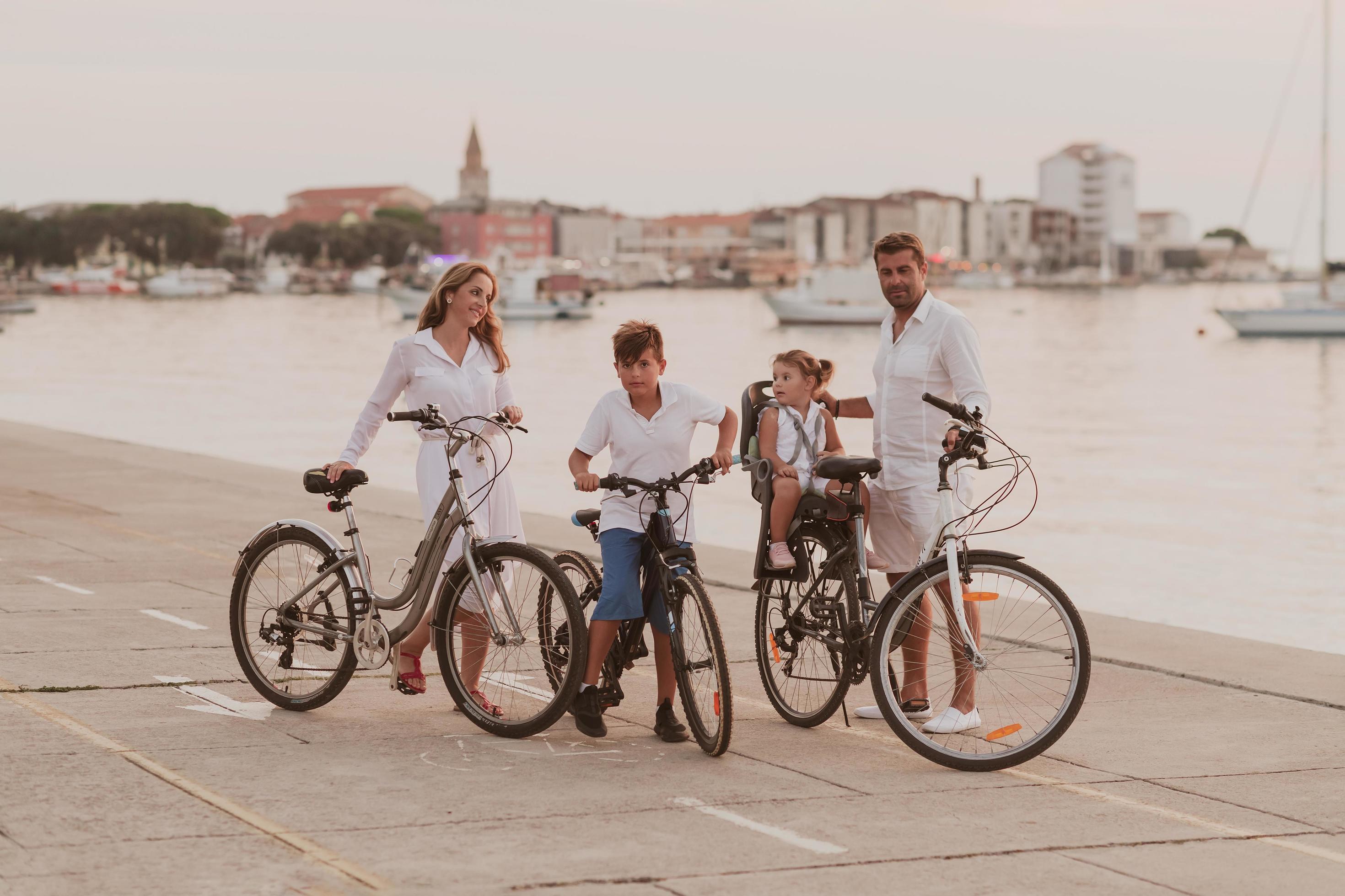 The happy family enjoys a beautiful morning by the sea riding a bike together and spending time together. The concept of a happy family Stock Free