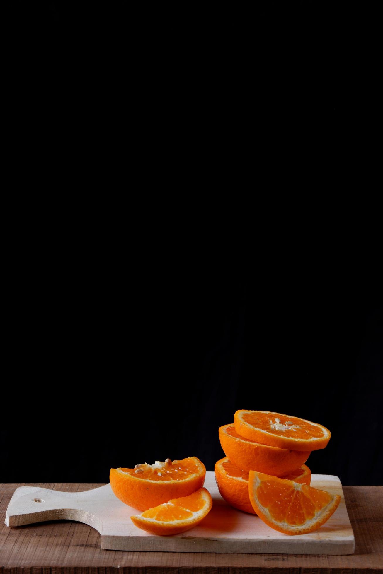 Orange slices on wooden cutting board on black background Stock Free