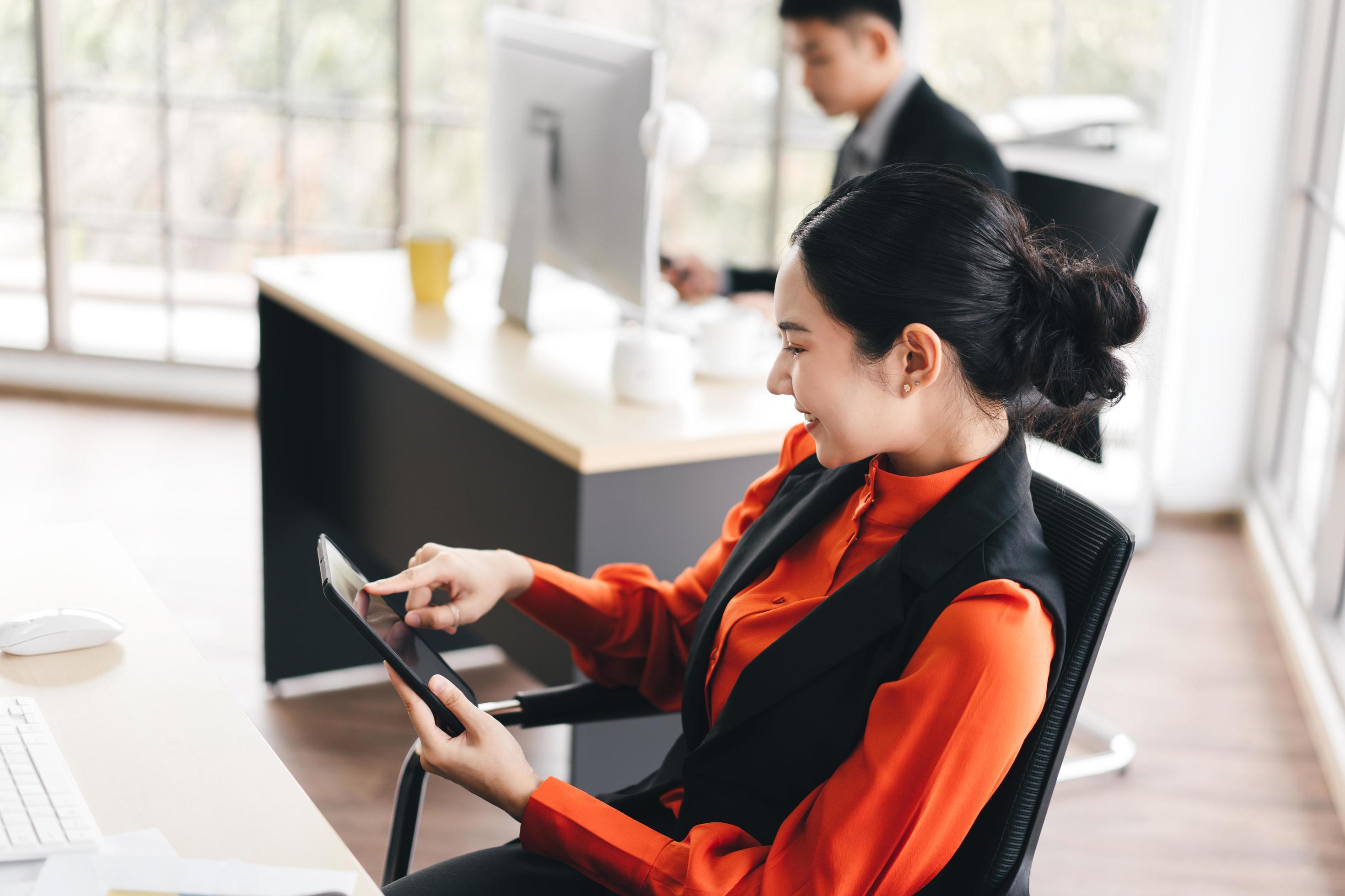 Young adult business woman using tablet for online media and stock market in office Stock Free