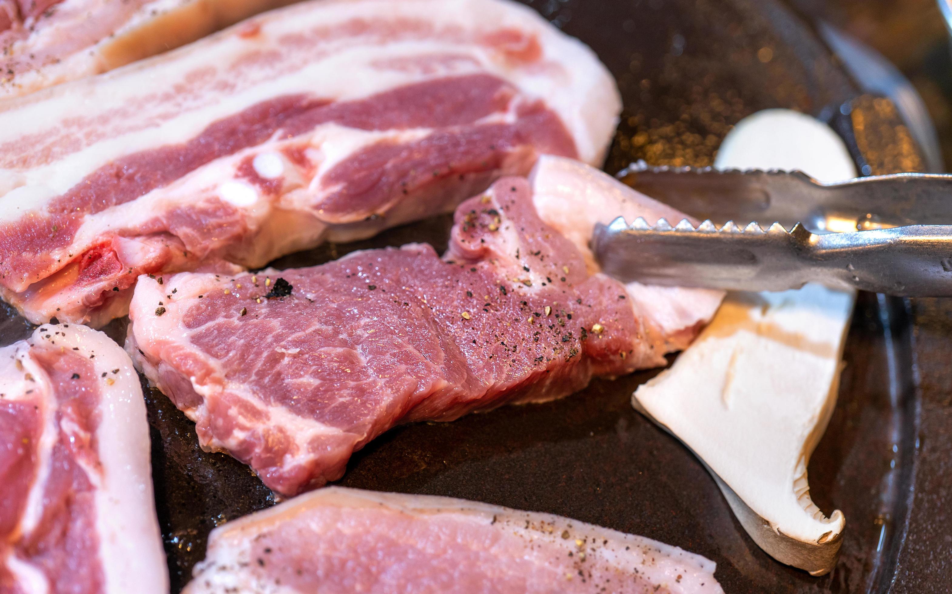 Pan-fried black pork meal in Korea restaurant, fresh delicious korean food cuisine on iron plate with lettuce, close up, copy space, lifestyle Stock Free