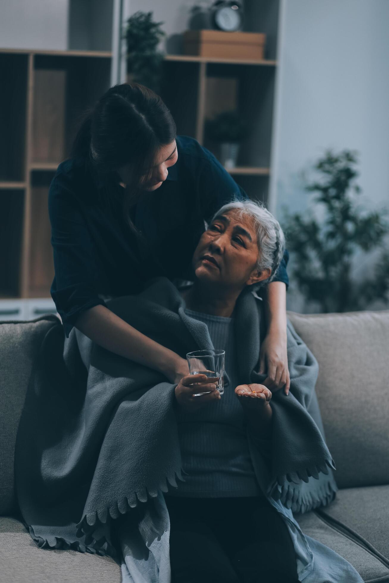 happy family Granddaughter takes care of her grandmother with warm cloths sitting on the sofa. Stock Free