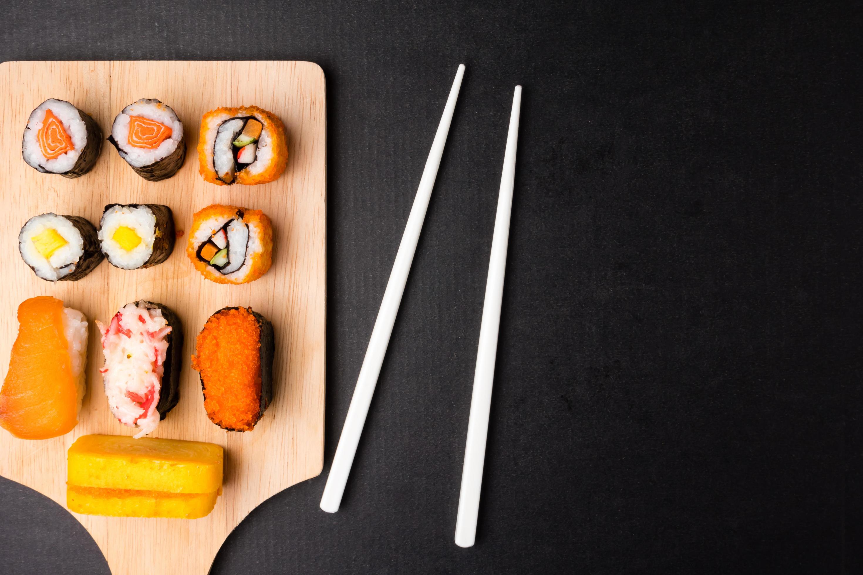 Top view of Sushi set on wooden tray with chopsticks on black background, Japanese food. Free space for text Stock Free