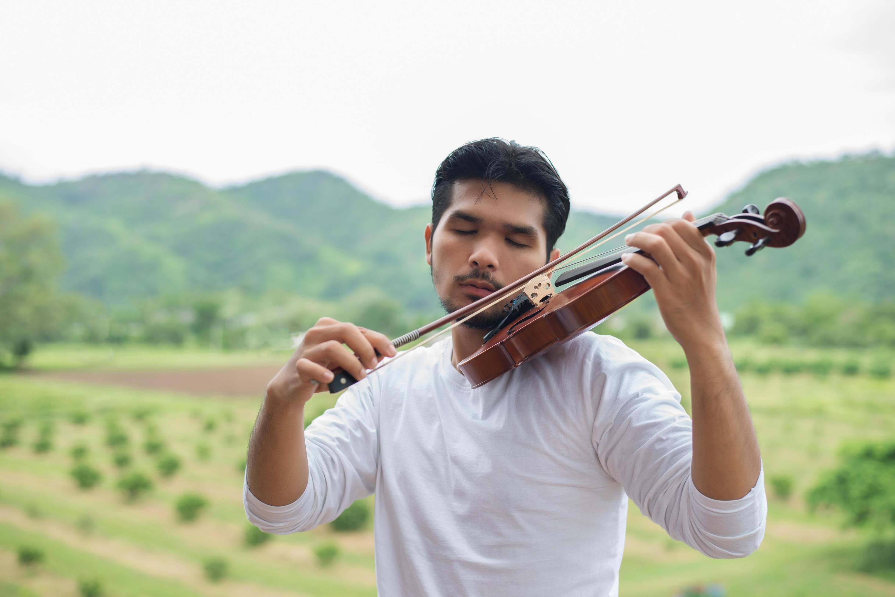 Young hipster musician man play violin in the nature outdoor lifestyle behind mountain. Stock Free