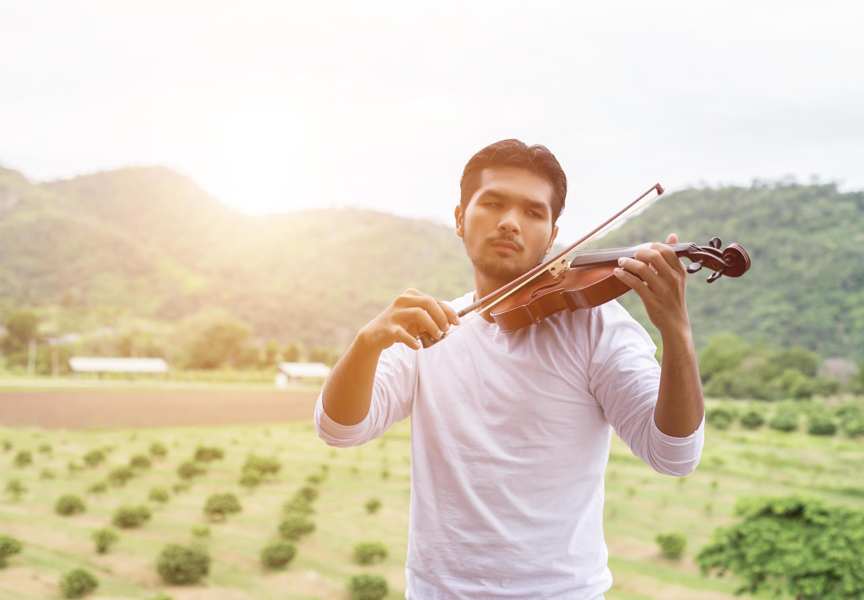 Young hipster musician man playing violin in the nature outdoor lifestyle behind mountain. Stock Free