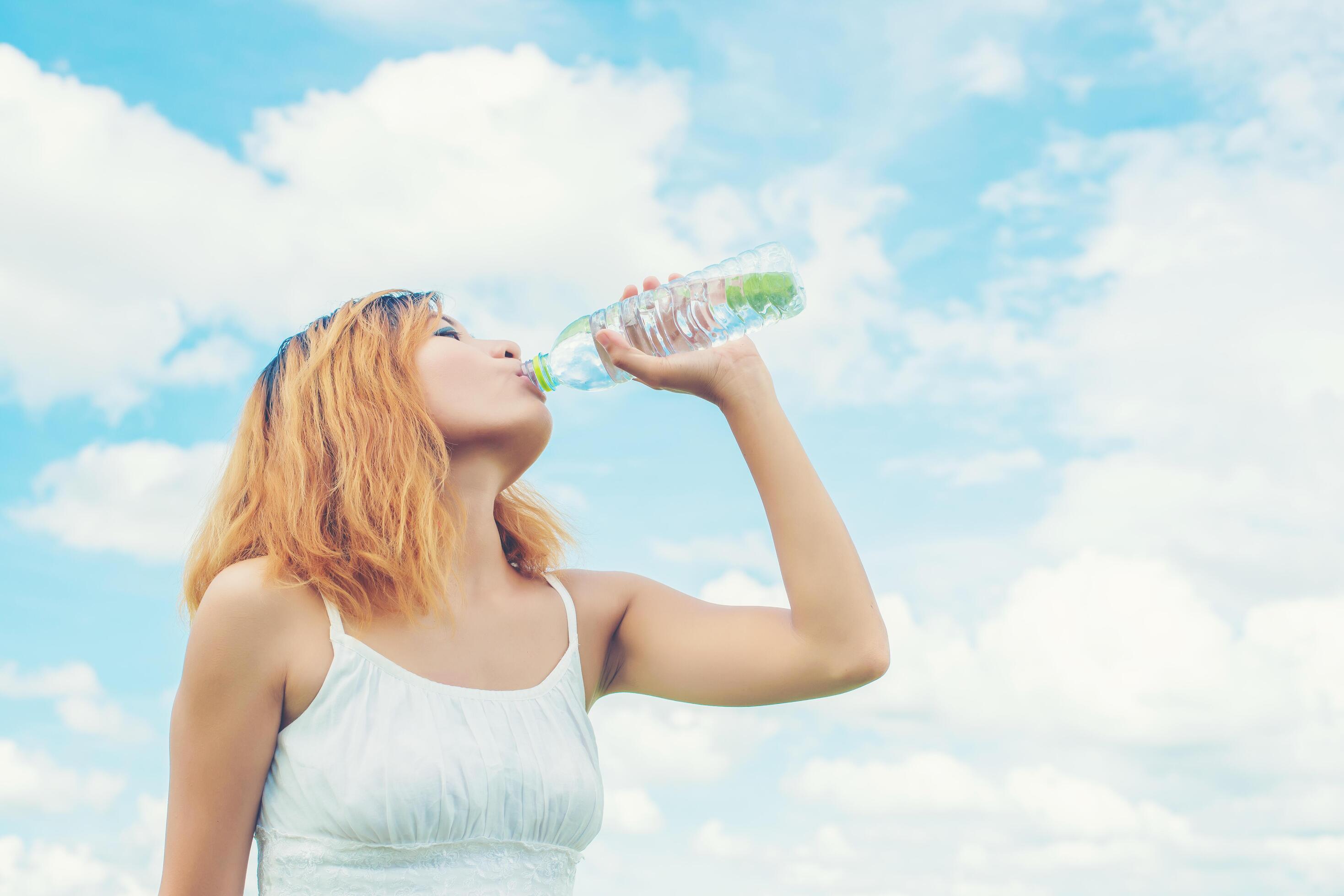 Women lifestyle concept young beautiful woman with white dress drinking water at summer green park. Stock Free