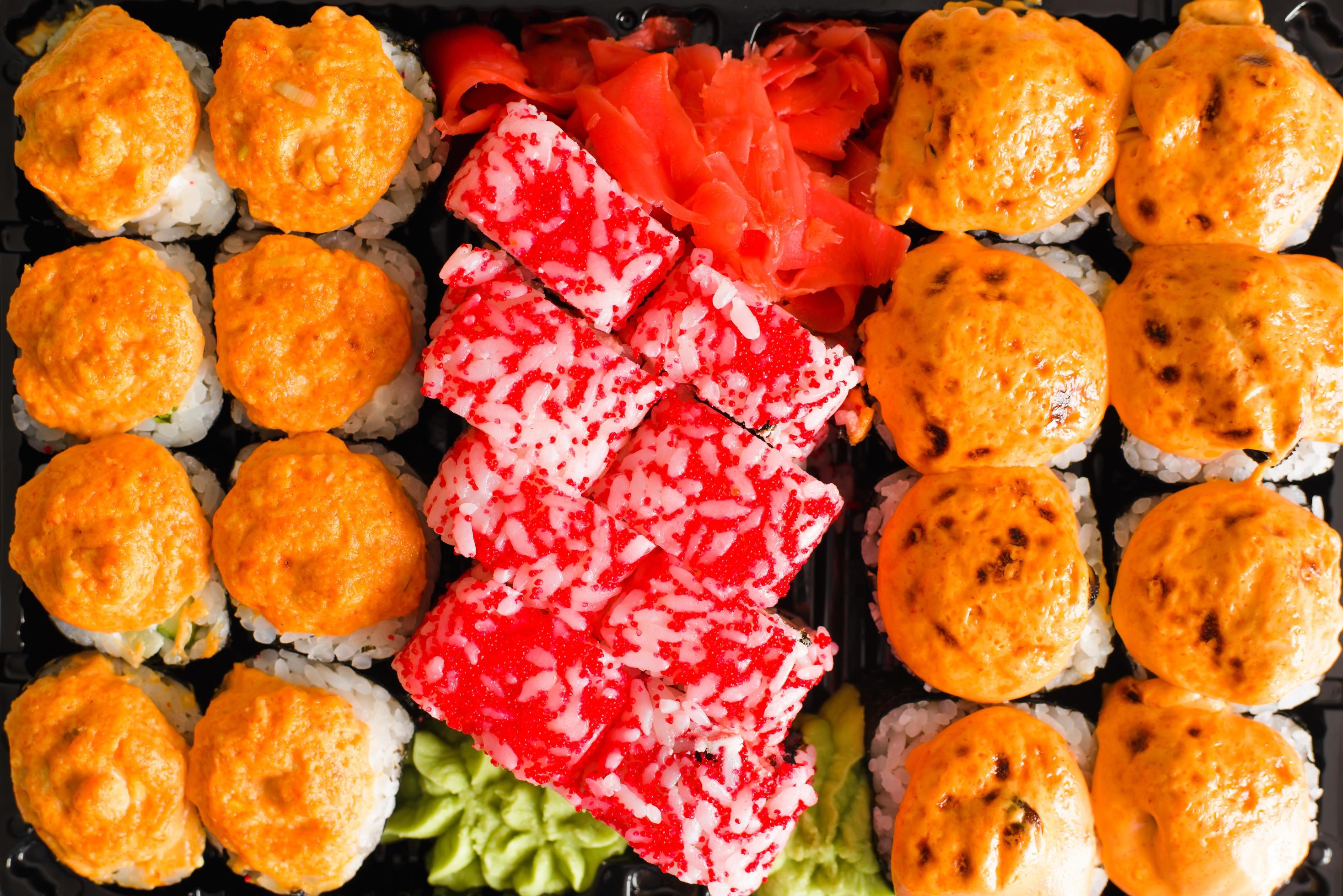 Japanese traditional food sushi and rolls, close-up. Set of baked and california rolls in a plastic container, top view Stock Free