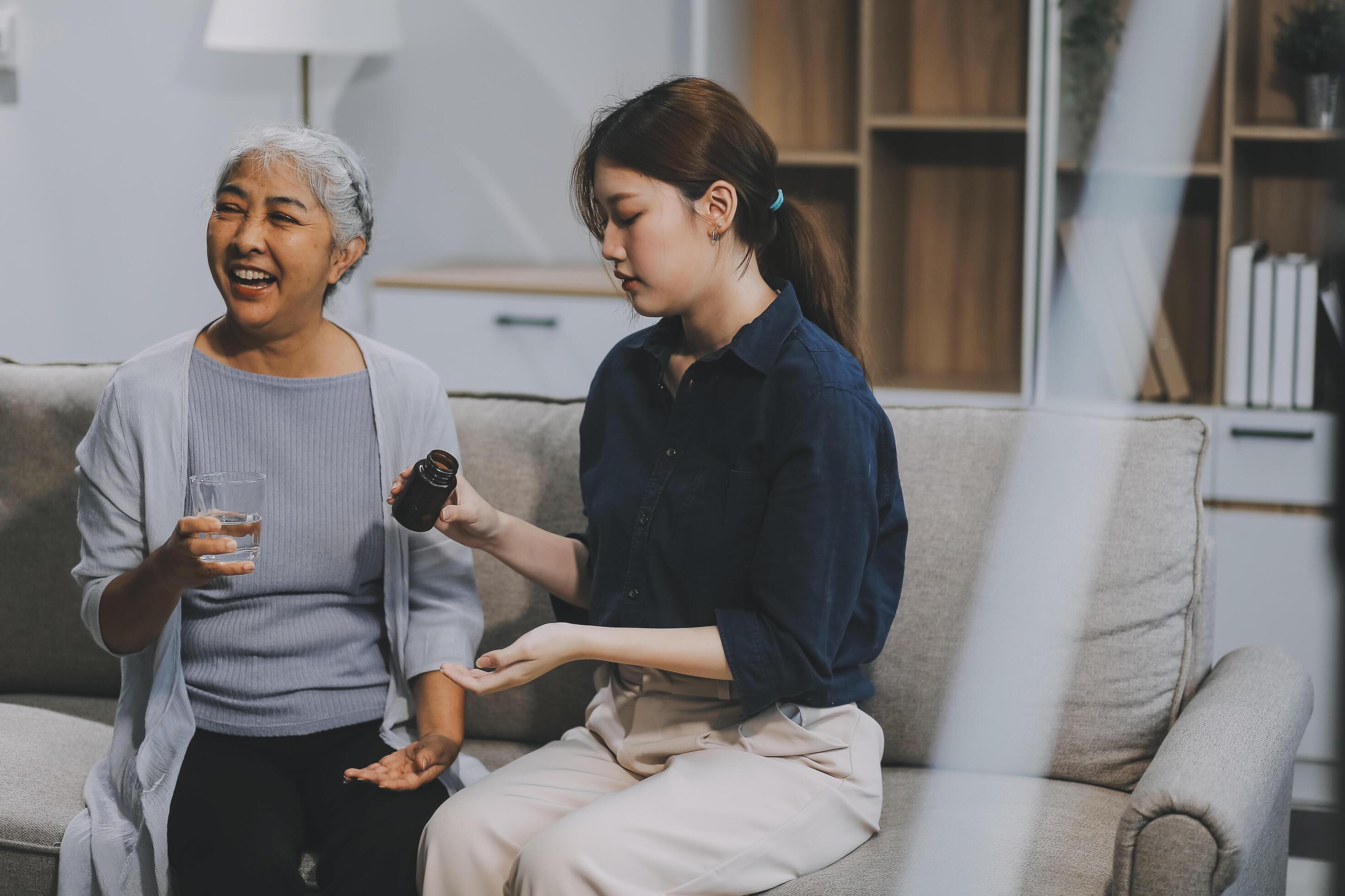 happy family Granddaughter takes care of her grandmother with warm cloths sitting on the sofa. Stock Free