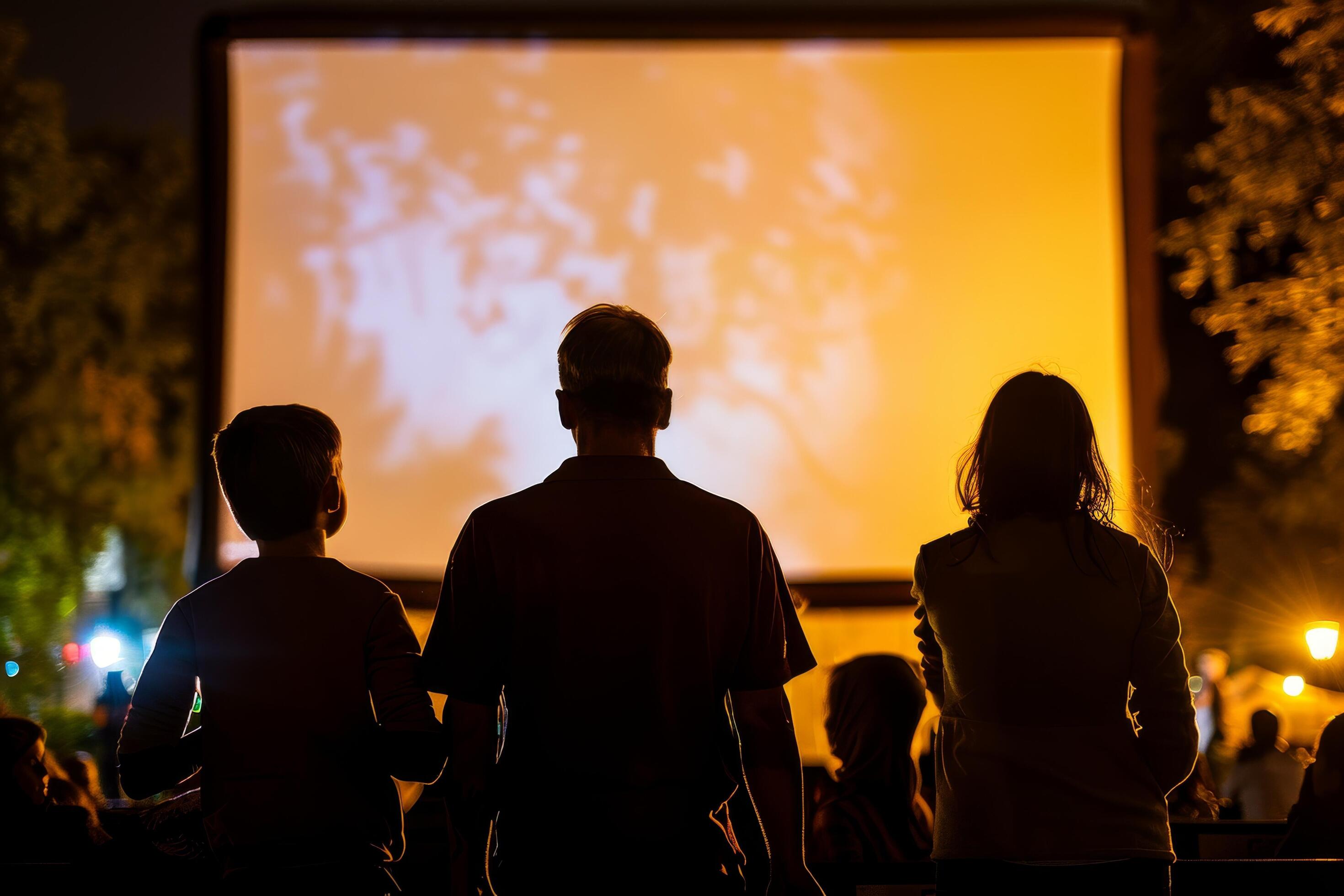 people are sitting in lawn chairs in front of a large screen Stock Free