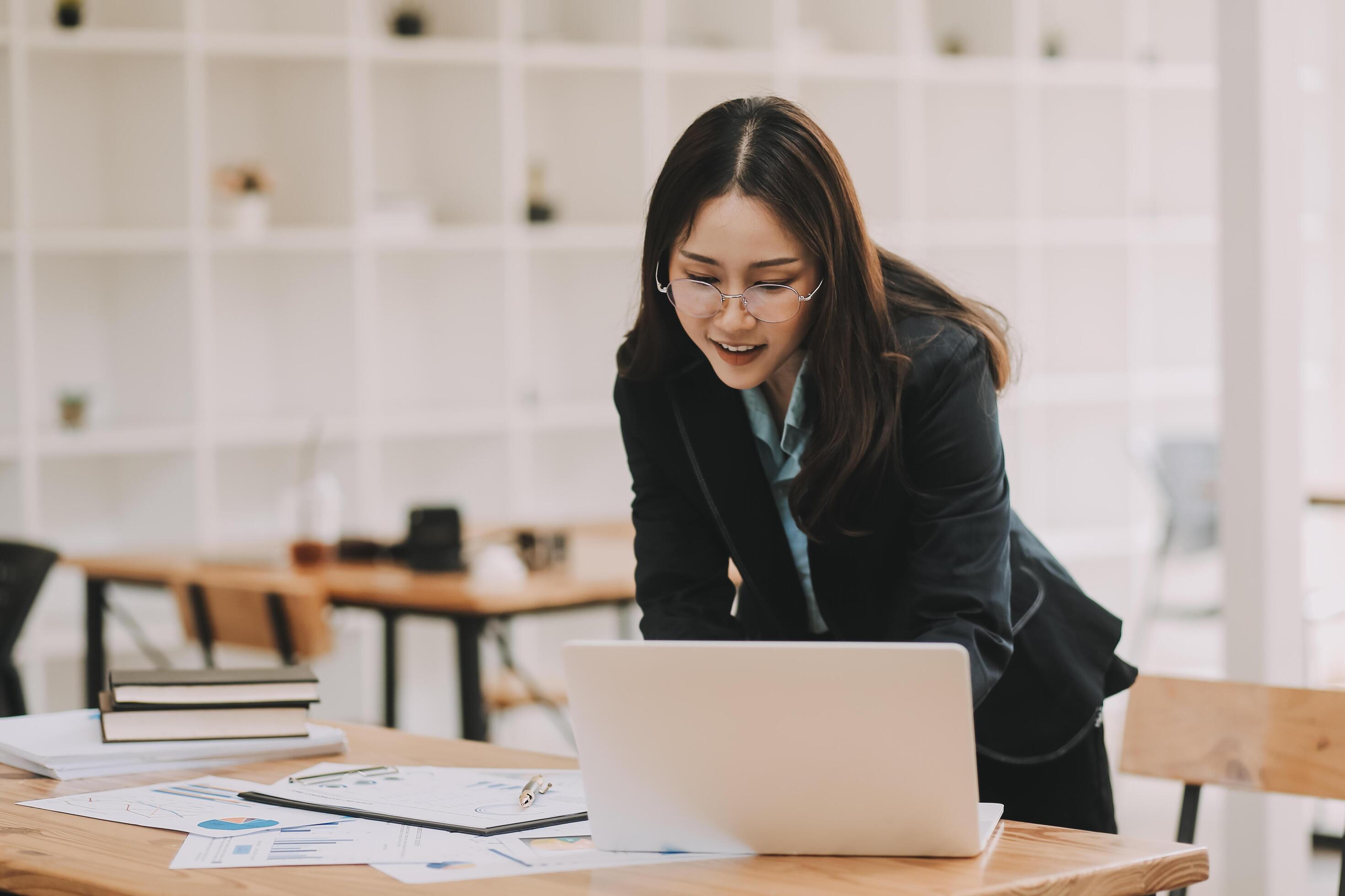 Happy young asian businesswoman sitting on her workplace in the office. Young woman working at laptop in the office. Stock Free