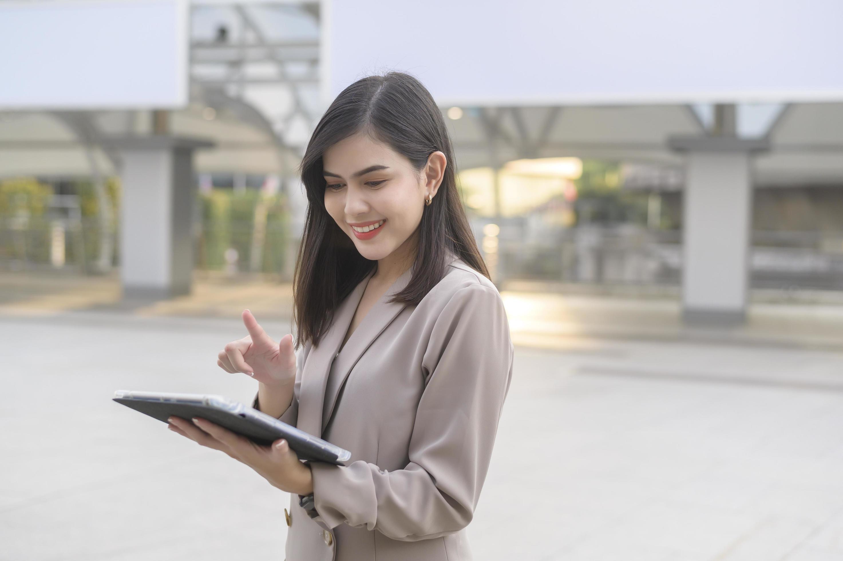 A young beautiful businesswoman is using tablet in Modern city , business technology , city lifestyle concept Stock Free