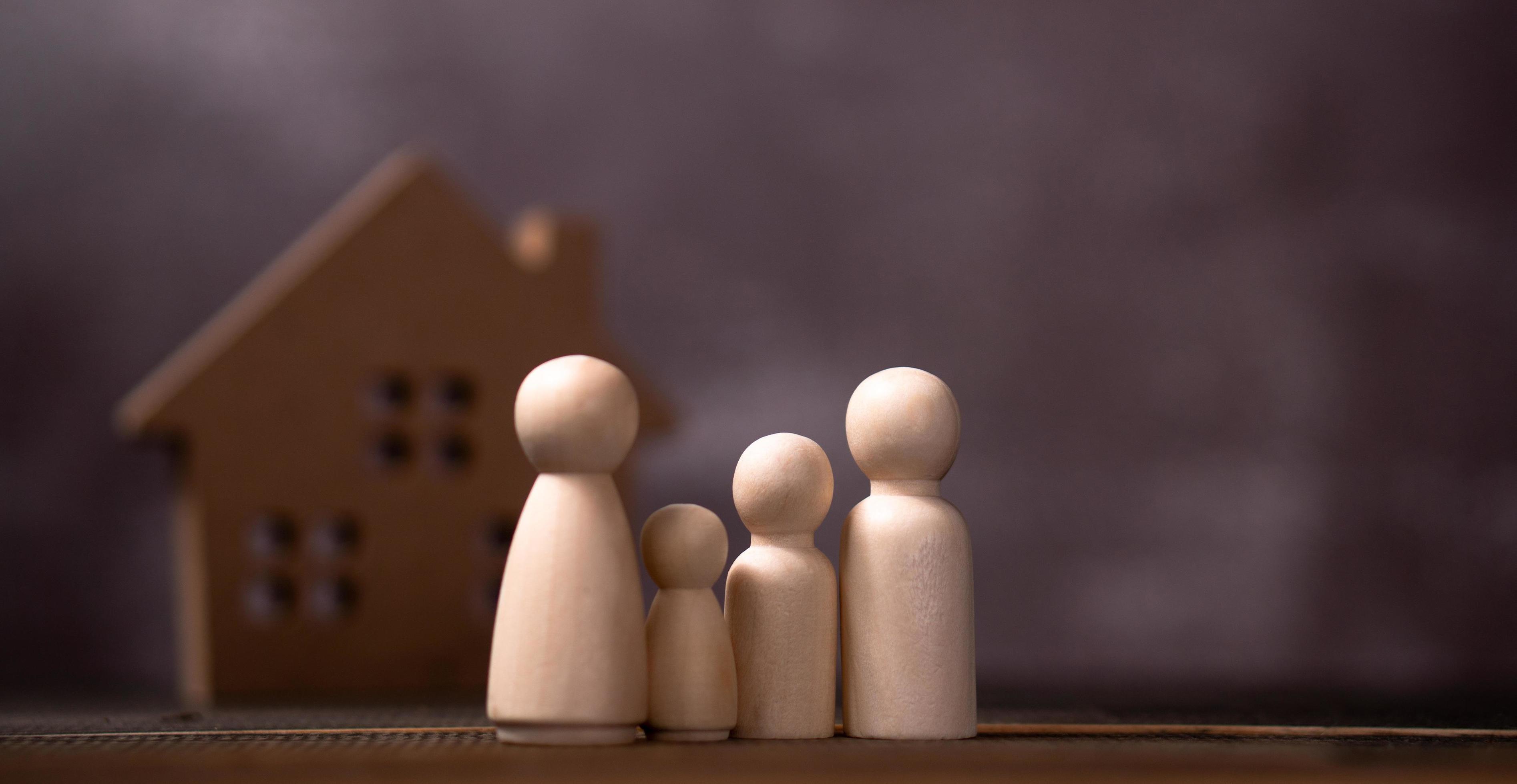 Wooden figures family standing in front of a wooden house. The concept of Protection and safety, Home Security, property insurance and house. Stock Free