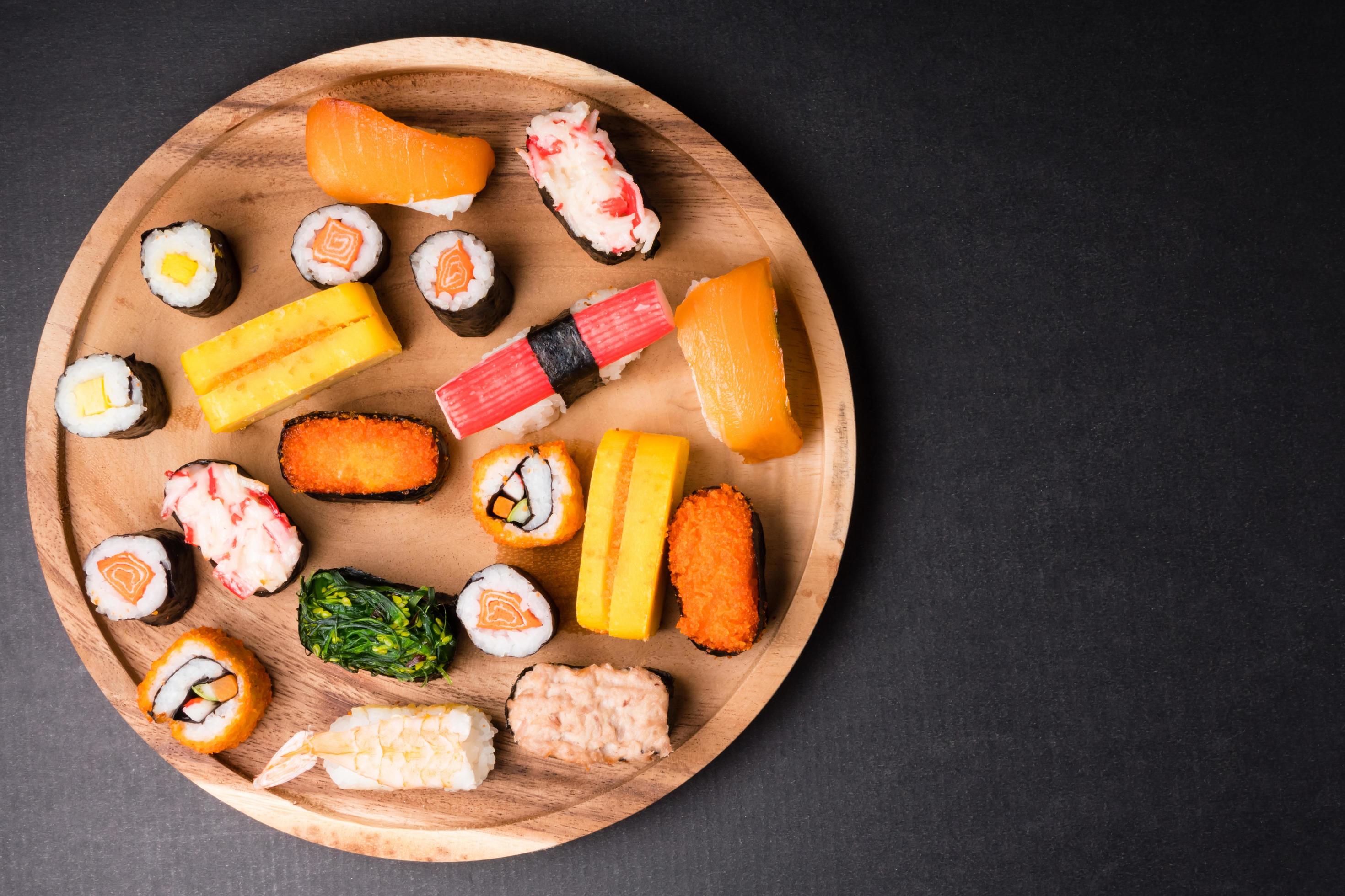 Top view of Sushi set on wooden plate on black background, Japanese food. Free space for text Stock Free