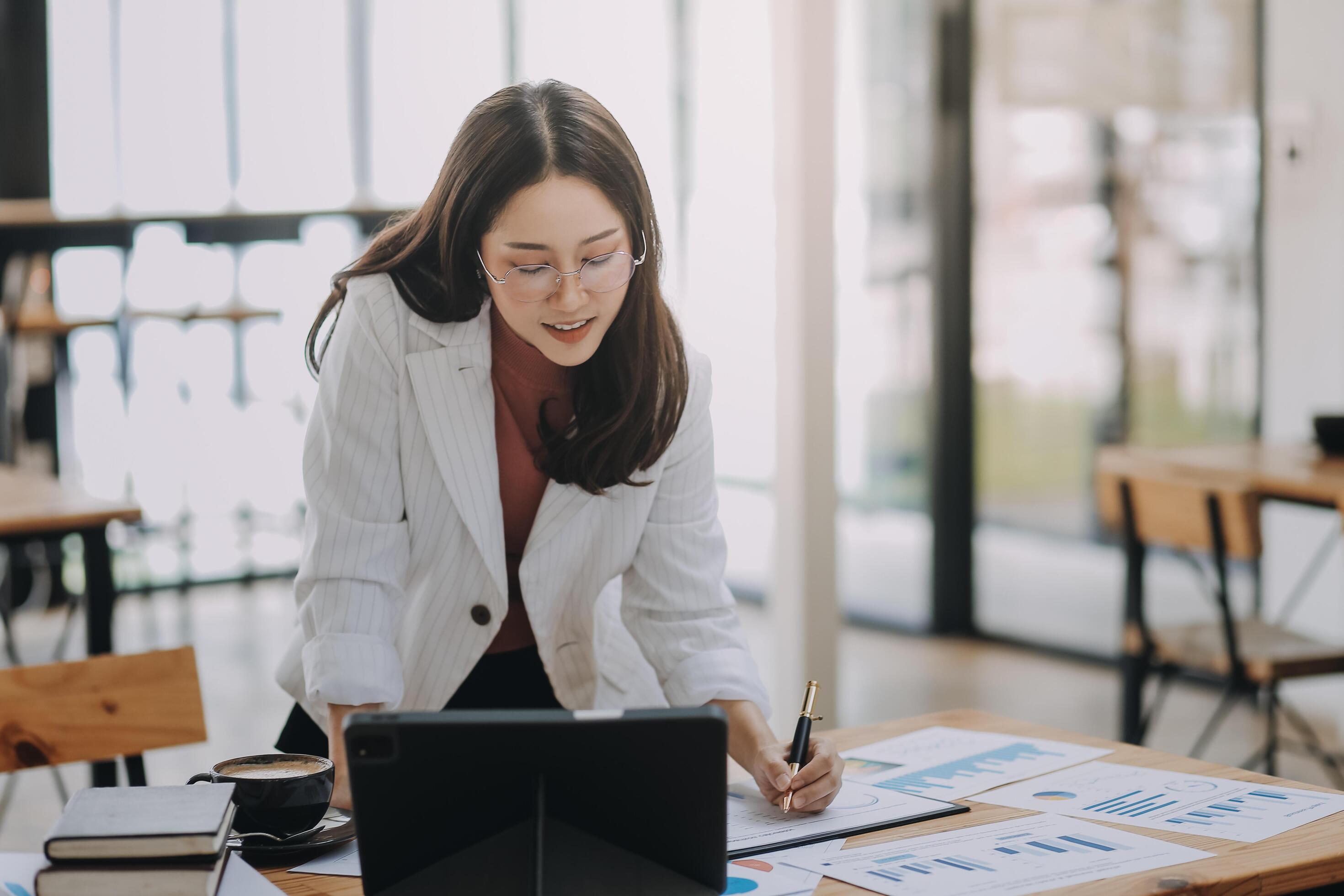 Happy young asian businesswoman sitting on her workplace in the office. Young woman working at laptop in the office. Stock Free