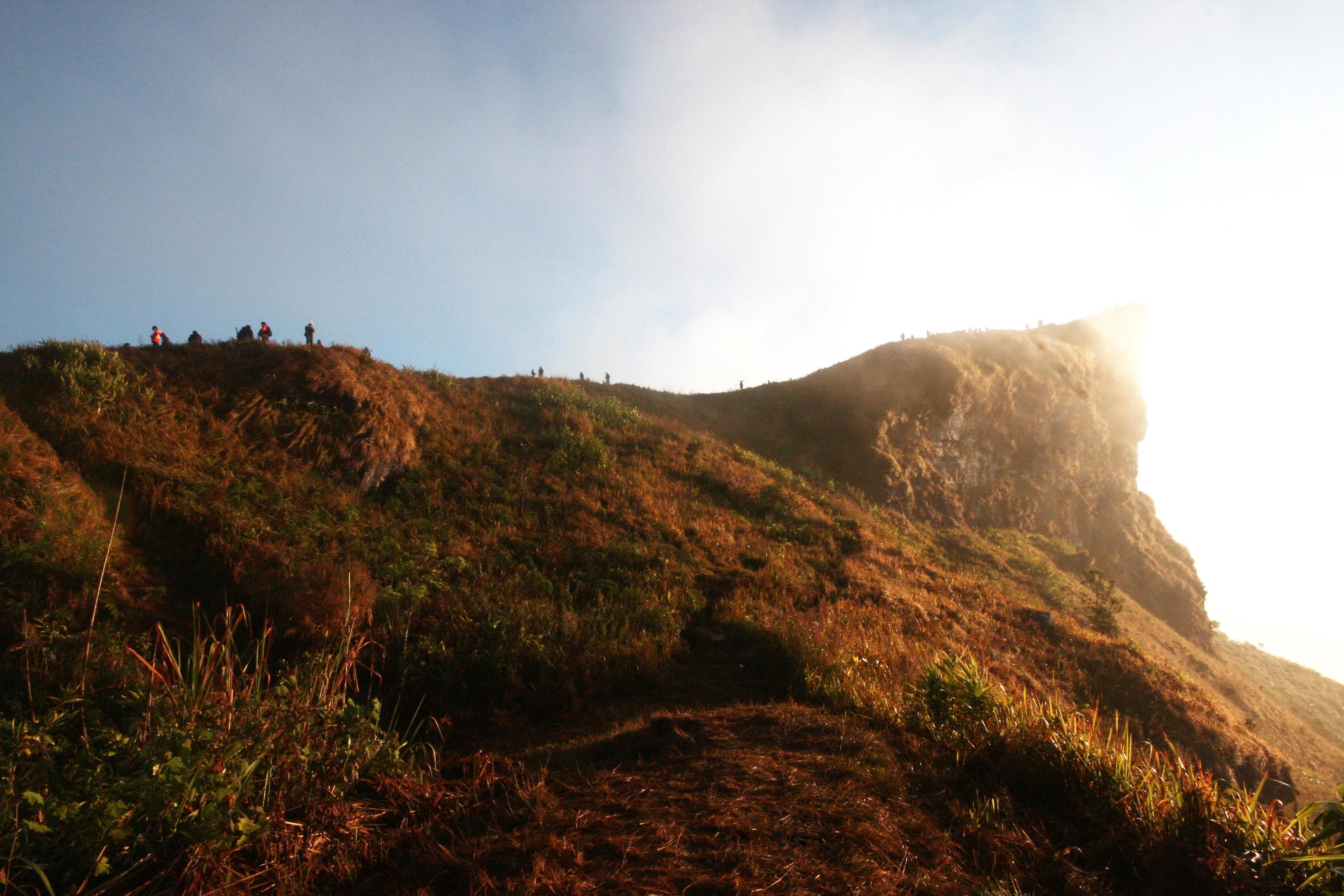 Silhouette tourist in valley of mountain with foggy and mist in winter of sunrise shining on the sky at Phu Chee Fah hill northern of Thailand Stock Free